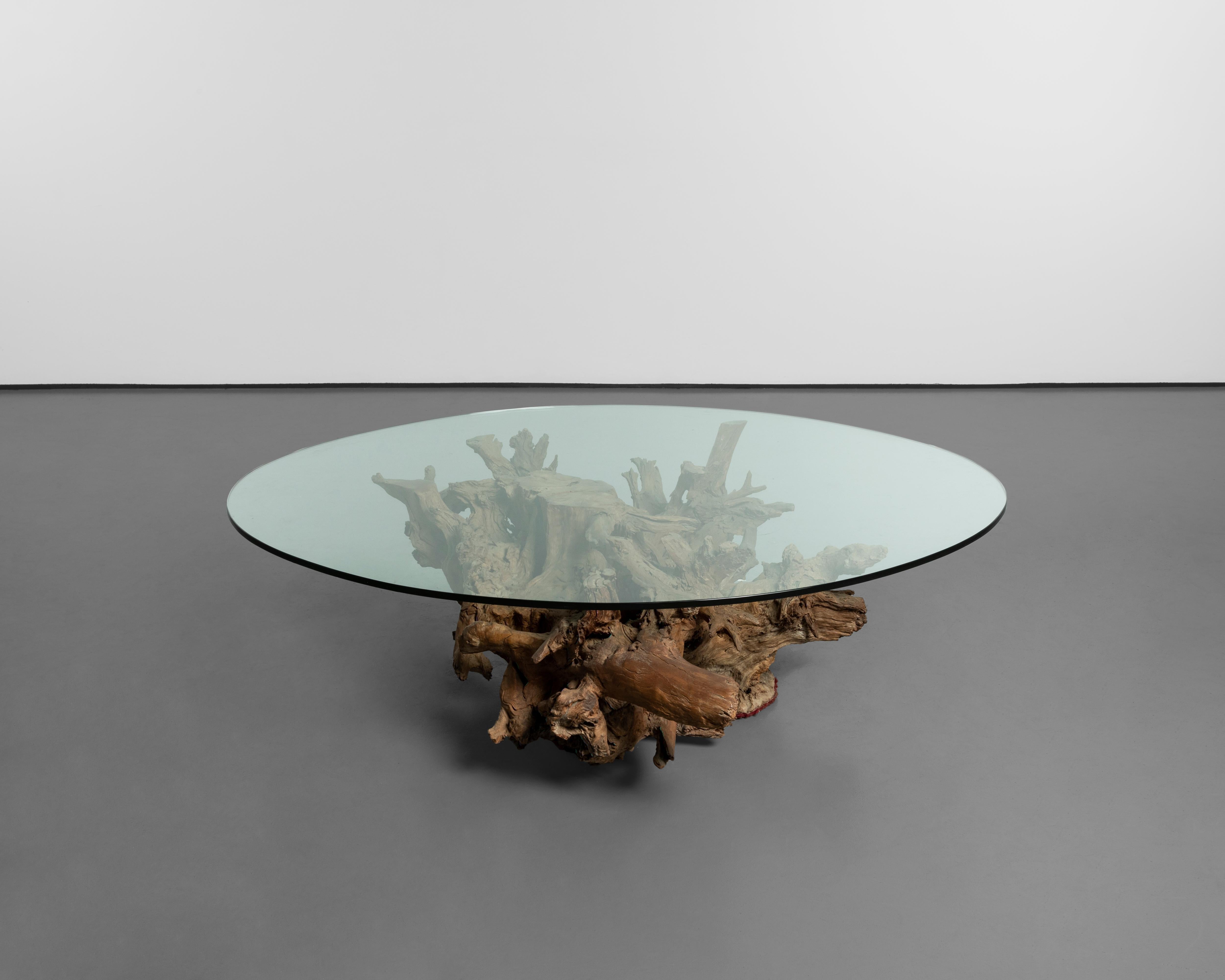 Esta mesa de centro, diseñada por José Zanine Caldas en 1970, encarna su profunda conexión con la naturaleza y su maestría en el diseño orgánico. Elaborada a partir de una pieza maciza de madera de raíz vinhática, la base conserva la forma natural e
