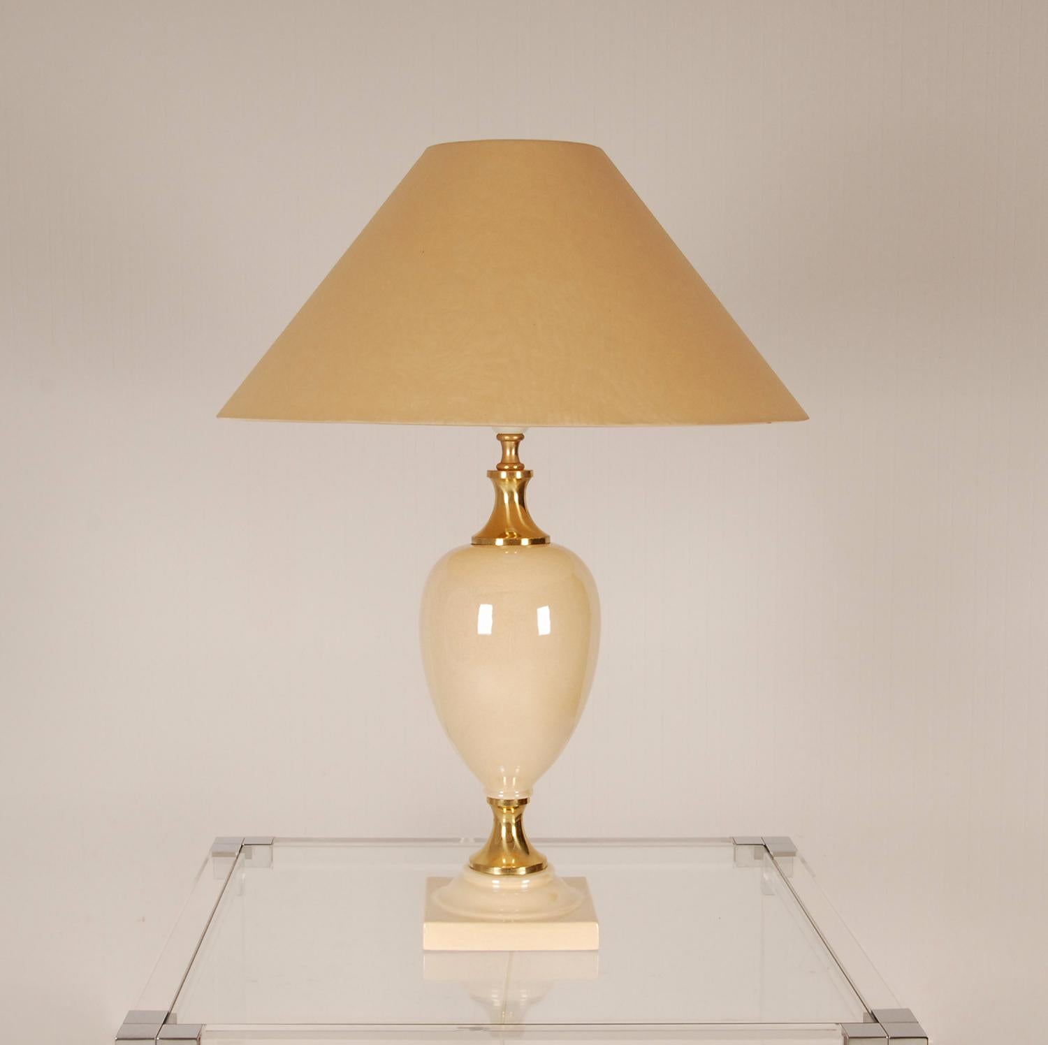 Mid Century 1970s Hollywood Regency glamorous and luxorious table lamp 
The lamp has an egg-shaped belly made of porcelain and a square foot
The belly rests on a brass stem and thee holder.
Colors: Gold and Champagne lustre glaze ( mother of