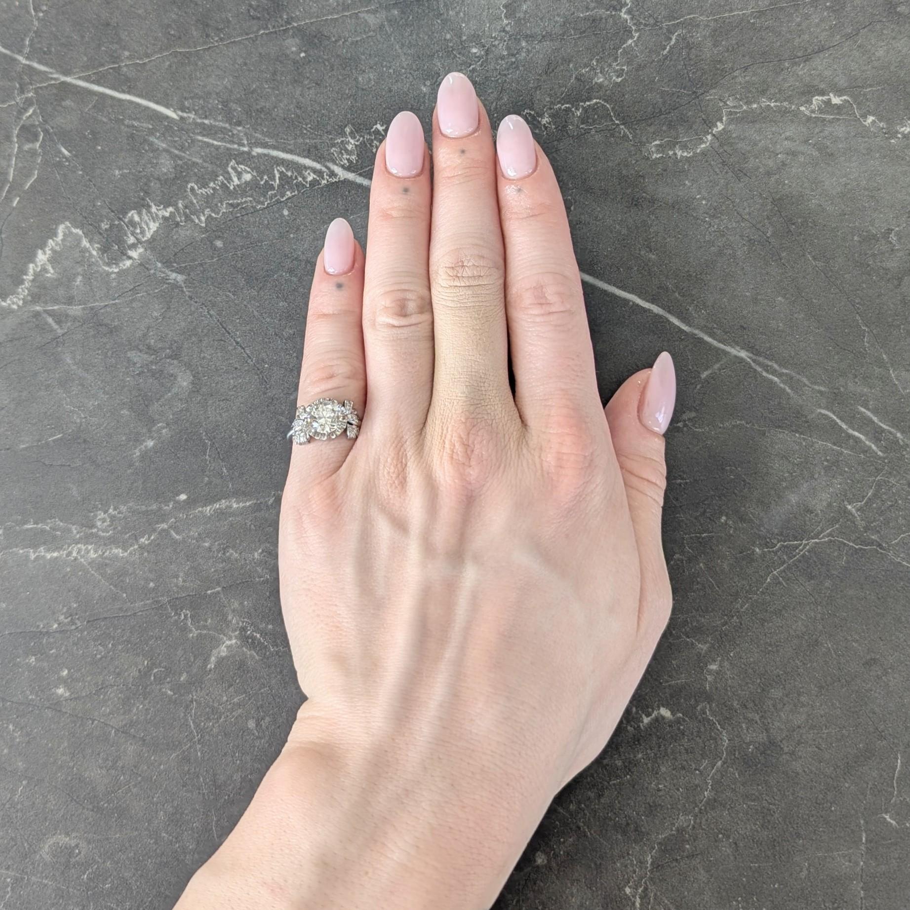 Centering an old European cut diamond weighing approximately 1.86 carat - L color with SI1 clarity
Prong set in a ruffled circular basket flaked by bow motif shoulders bead set with diamonds
Single cut and weighing approximately 0.14 carat total
Eye