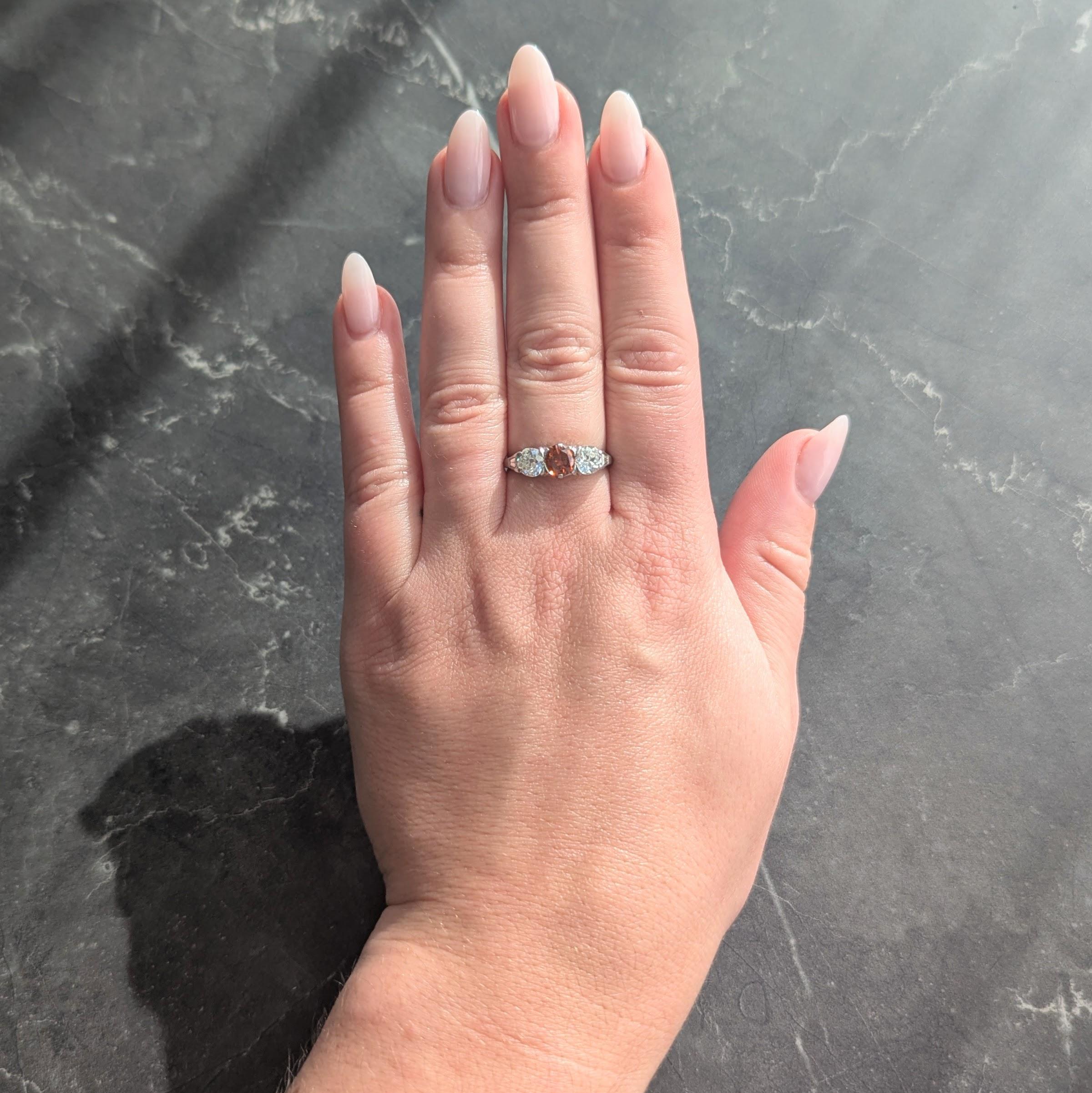 Al centro un diamante colorato taglio brillante rotondo del peso di 0,72 carati.
Arancio bruno intenso con un colore naturale uniforme e una purezza SI1.
Affiancato da due diamanti taglio vecchia miniera ben assortiti
Pesa circa 1,12 carati in