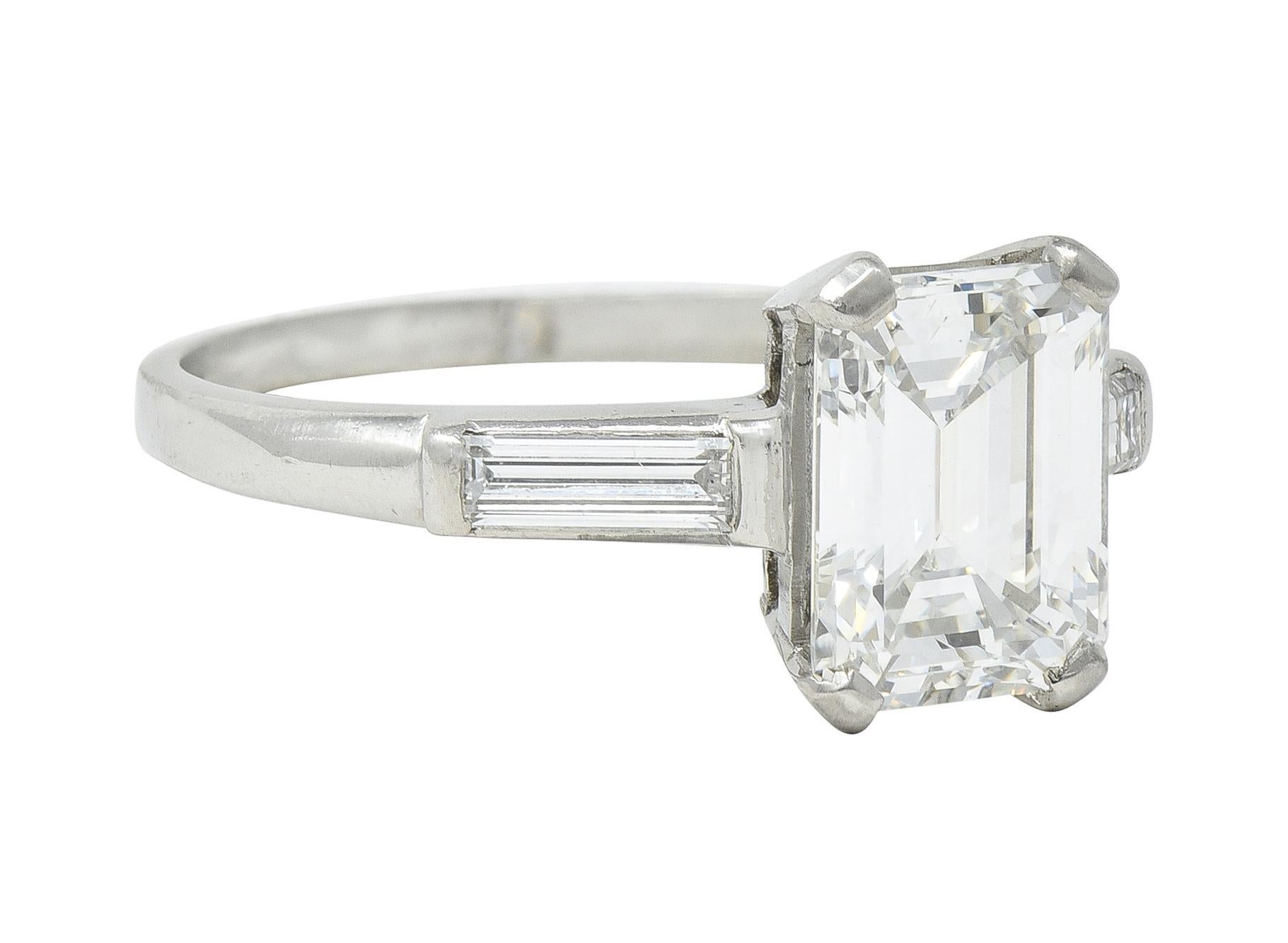 Engagement ring centers a prong set emerald cut diamond weighing 1.83 carats - F color with VS2 clarity
Flanked by two bar set and well matched baguette cut diamonds - weighing approximately 0.28 carat total
Completed by high polished shank
Stamped