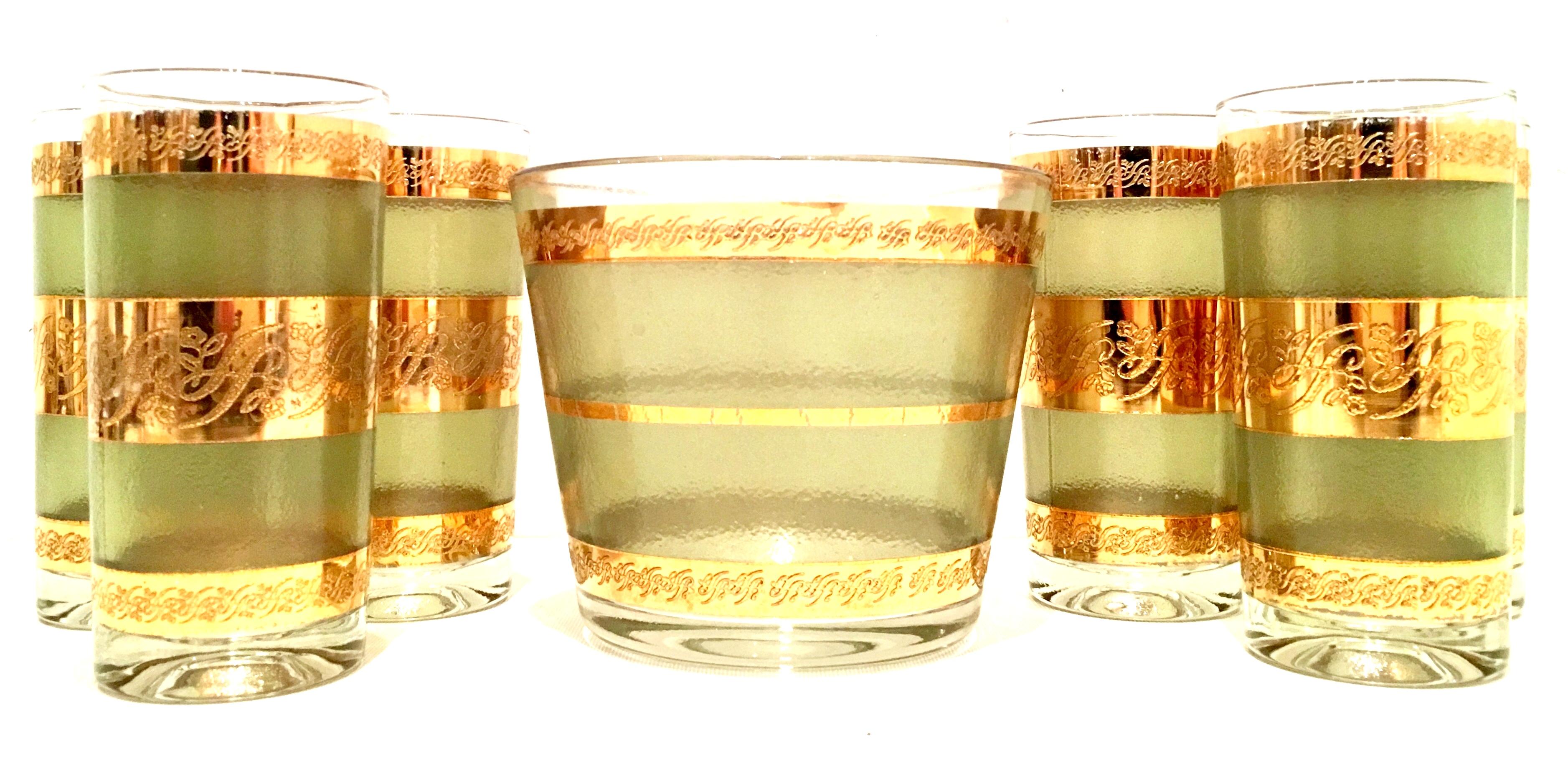 Mid-Century 22-karat gold band and textured green glass drinks set of seven pieces.
This drinks set features green textured glass with 22-karat gold scroll detail banding pattern.
Set includes, one ice bucket and six high ball glasses. 
High ball
