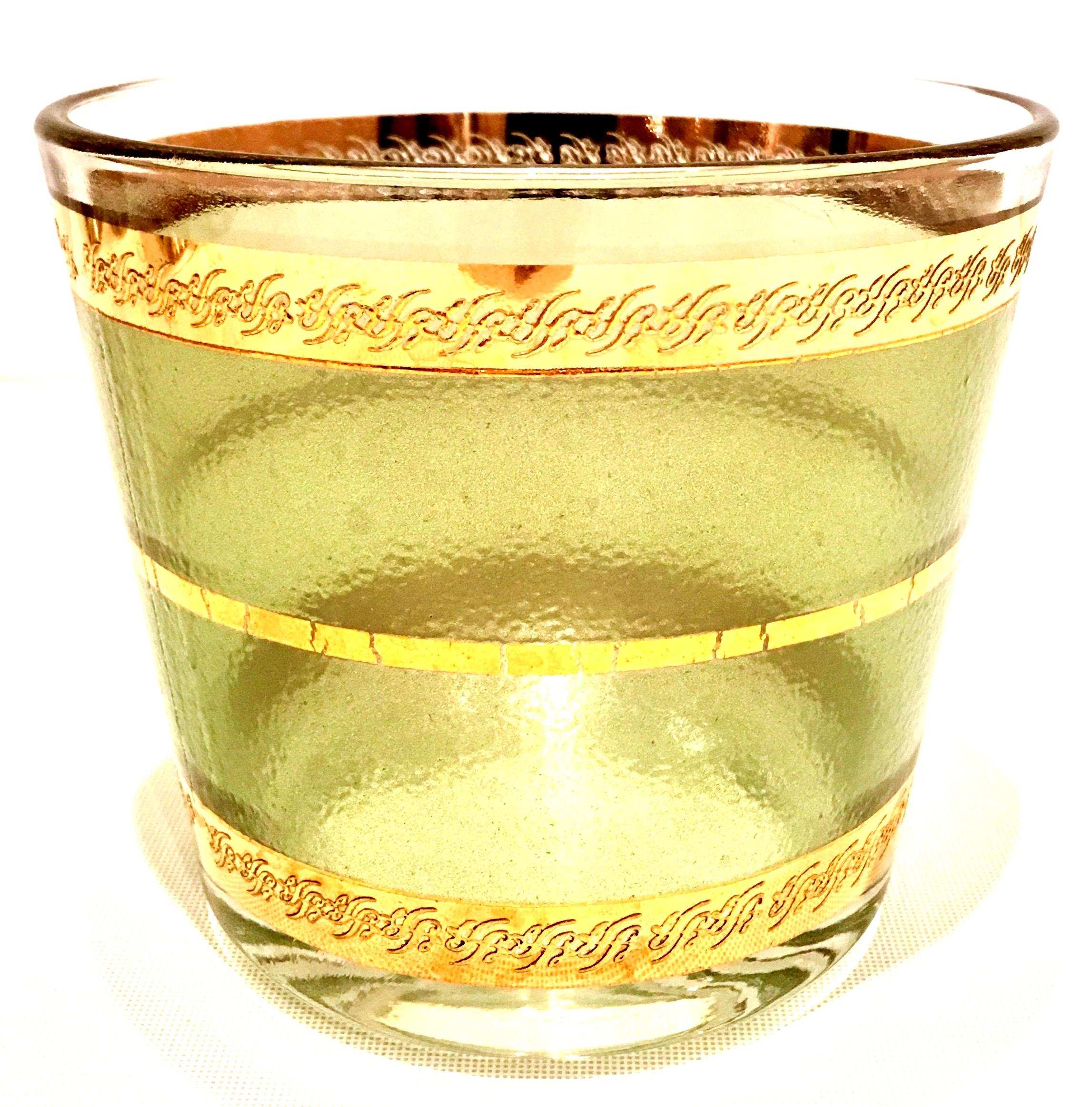 Mid-Century 22-karat gold band and textured green glass drinks set of seven pieces.
This drinks set features green textured glass with 22-karat gold scroll detail banding pattern.
Set includes, one ice bucket and six high ball glasses.
High ball
