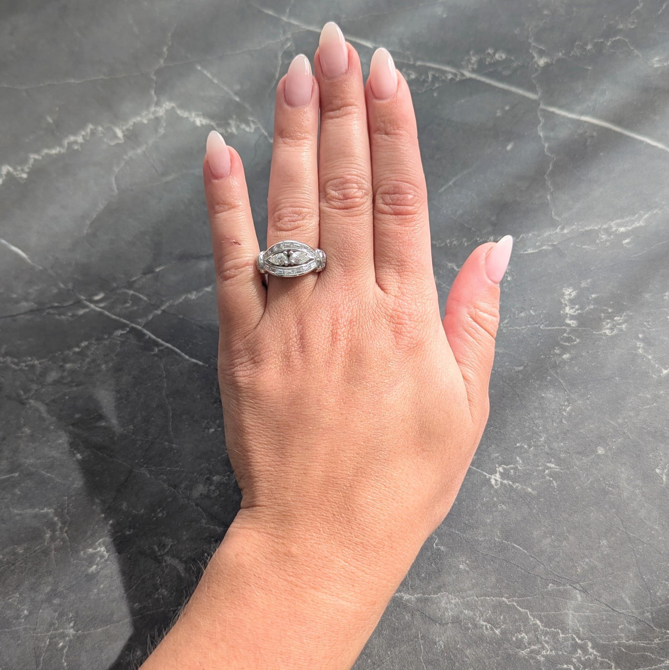 Conçue comme une forme bombée percée centrée sur deux diamants taille poire en miroir.
Poids total d'environ 0,75 carat - Couleur H et pureté VS2
Serti à l'aide d'un halo et de stations d'épaulement arquées.
Serti en canal avec des diamants de