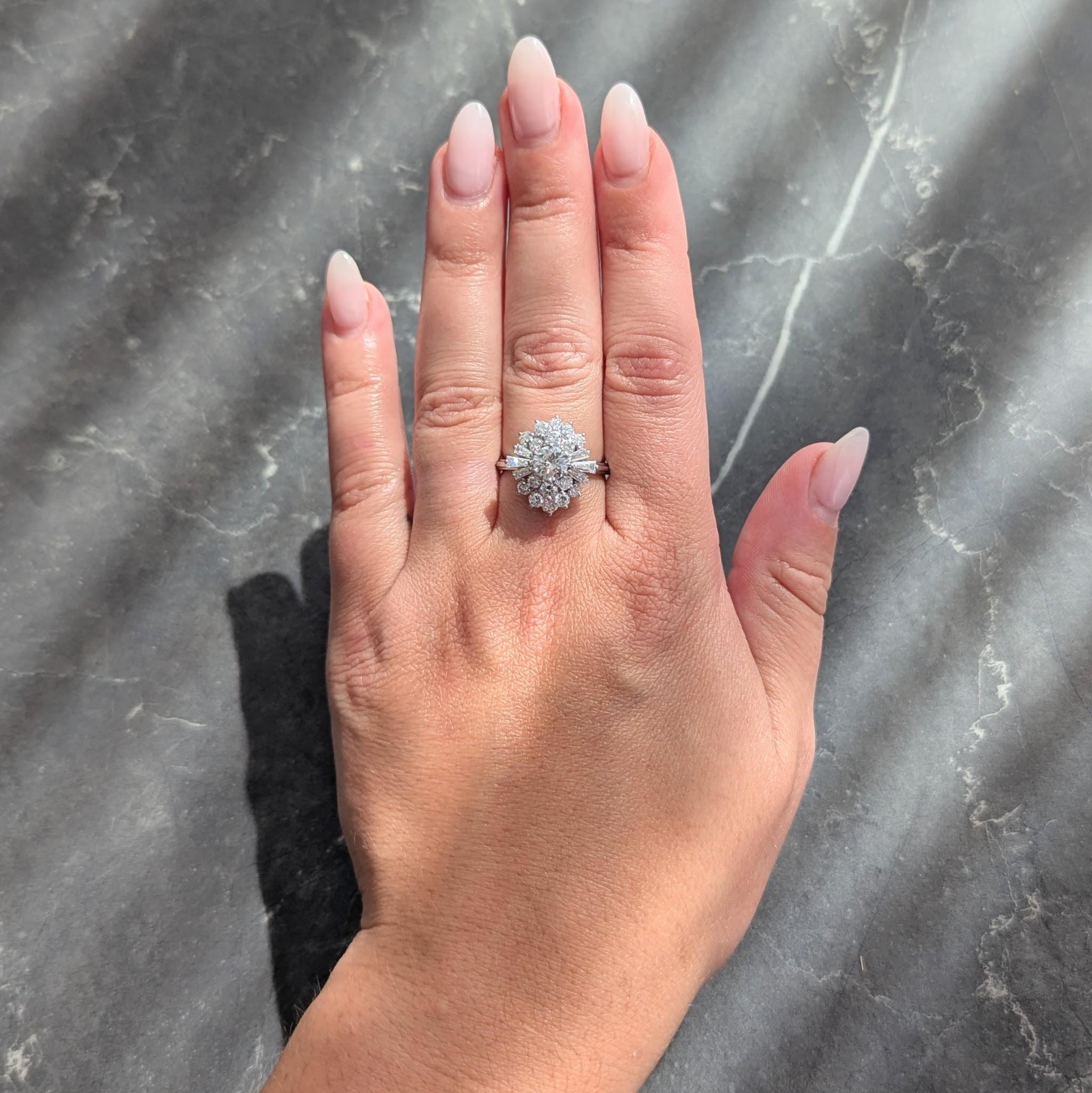 Gestaltet als gestufter Ring im Cluster-Stil mit einem in Zacken gefassten Diamanten im Übergangsschliff in der Mitte
Mit einem Gesamtgewicht von etwa 0,69 Karat - Farbe G mit Reinheit VS2
Umgeben von Diamanten im Baguetteschliff, die sich