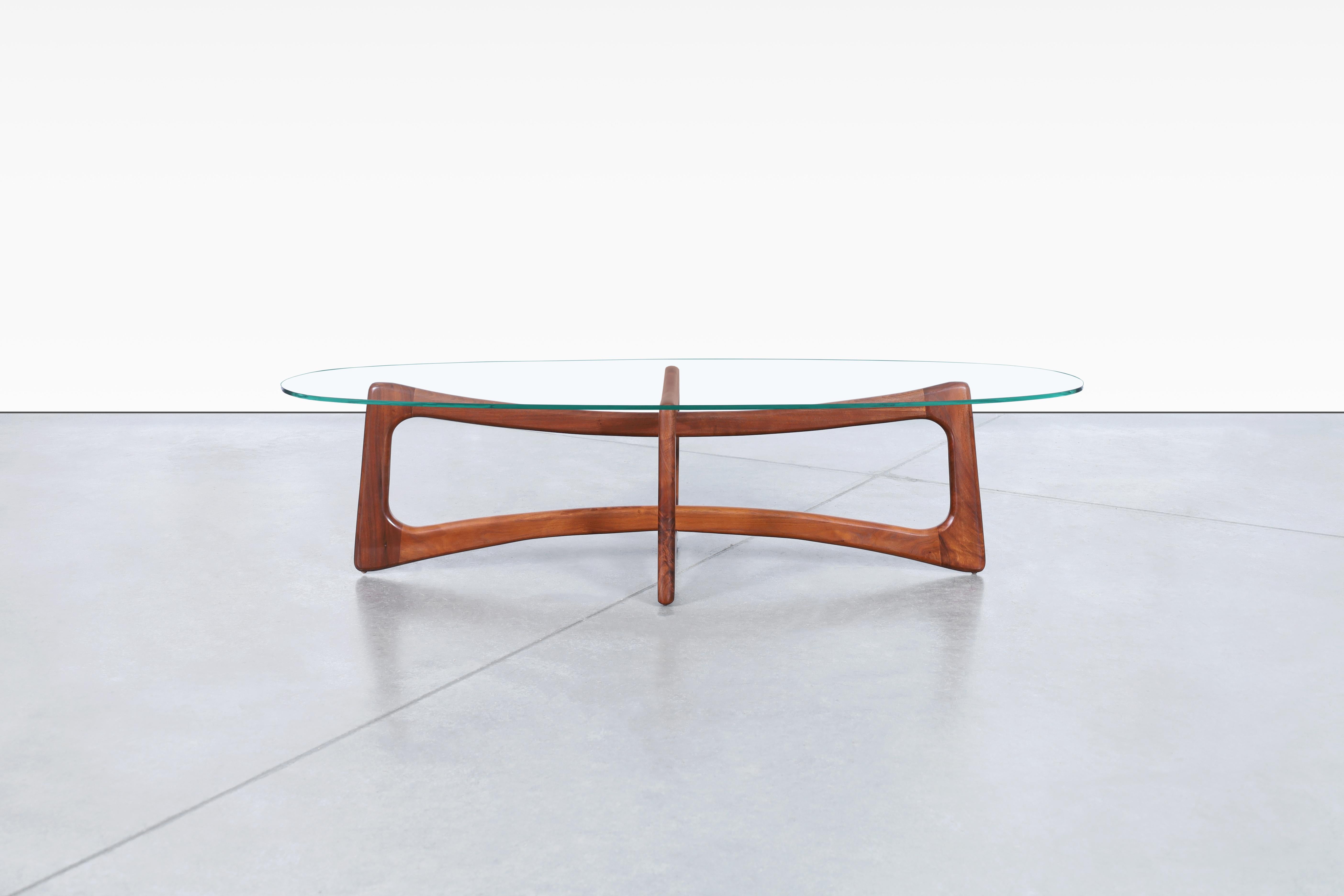 This mid-century coffee table is a stunning piece of furniture that is sure to impress. Designed by Adrian Pearsall for Craft Associates in the 1960s, this coffee table is the model 2454-TGO. The table has been refinished to bring out its natural