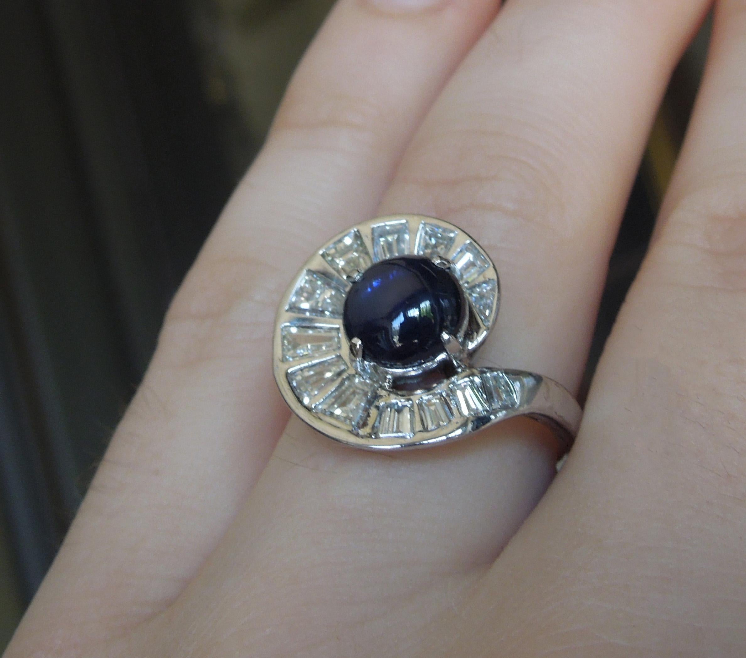 In a Mid-Century timeless design, this Star Sapphire & Baguette Piano Key Platinum Cocktail Ring features a central 2.57 carat Iridescent Rich Blue Sapphire spiraled by 1.35 carats of unusually large Tapered Baguette cut Nearly Colorless Nearly