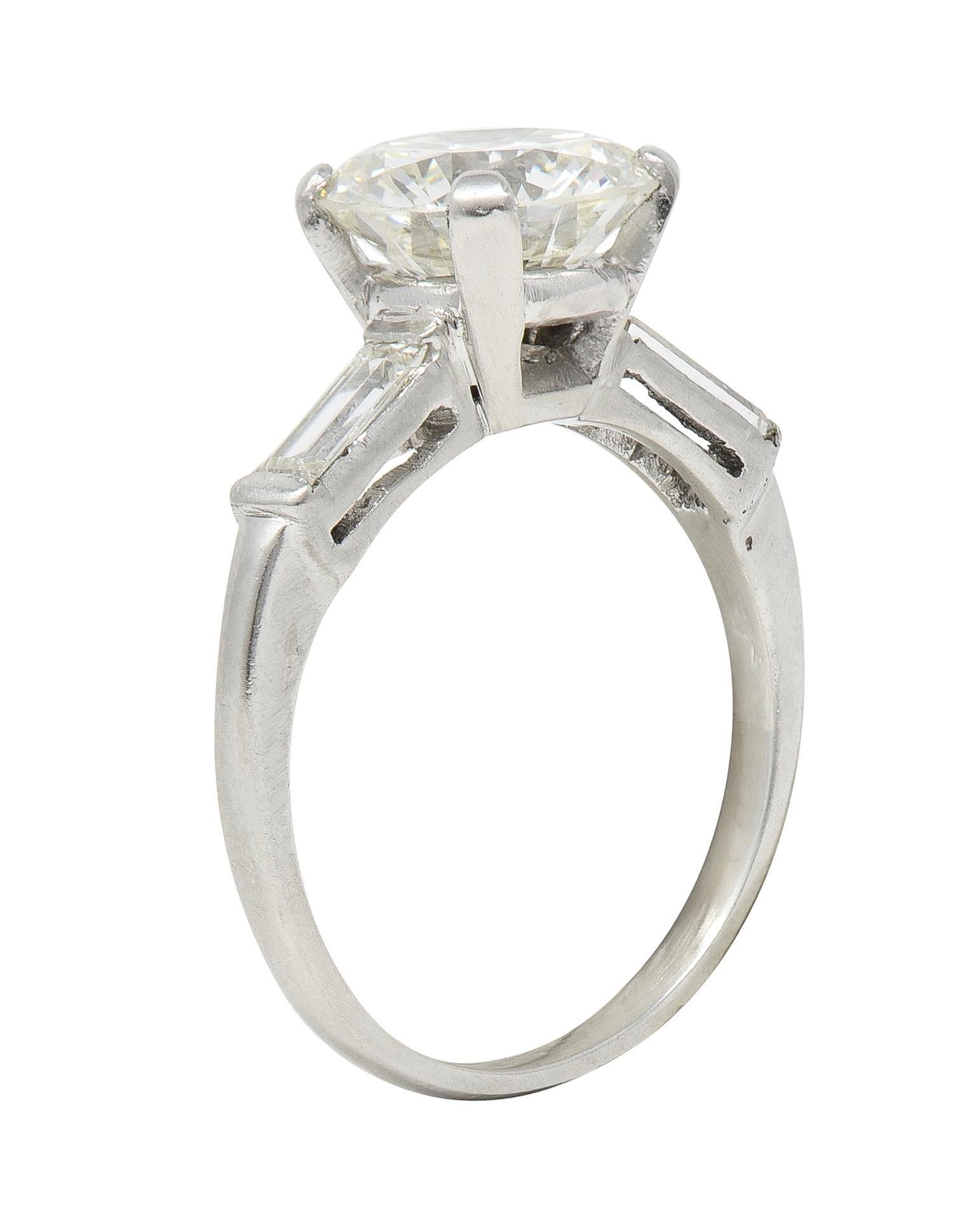 Centering a transitional cut diamond weighing 2.38 carats - J color with VS2 clarity
Prong set in basket and flanked cathedral shoulders 
Bar set with baguette cut diamonds 
Weighing approximately 0.28 carat total 
Well matched to center 
Tested as