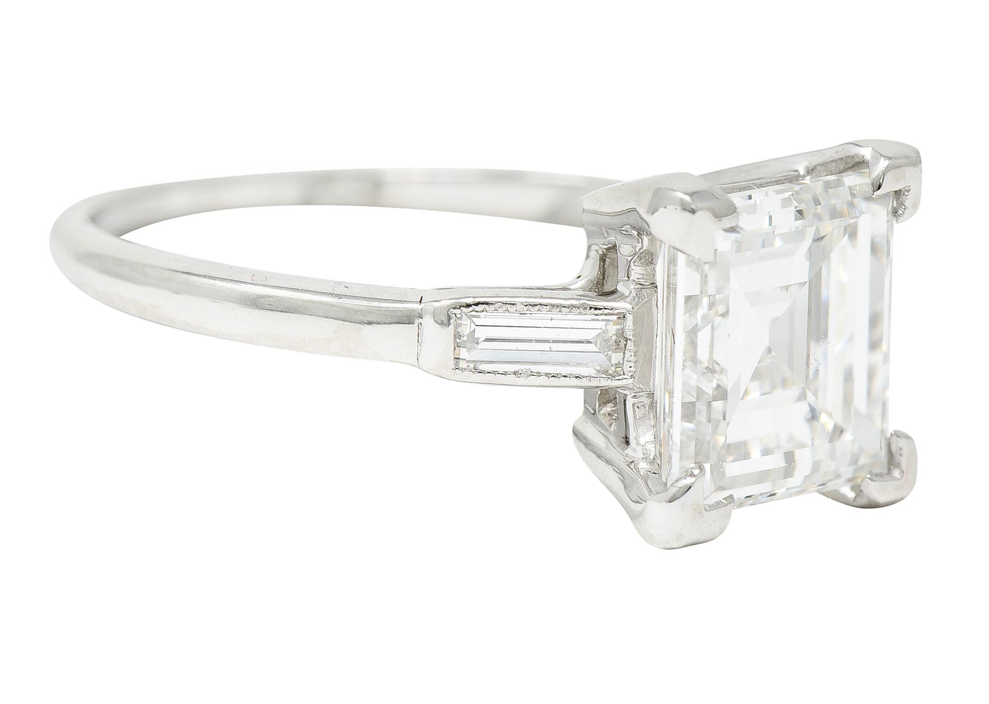 Featuring a square step cut diamond weighing 2.56 carats - D color with VS1 clarity. Basket set with V prongs and flanked by subtle cathedral shoulders. Flush set with straight baguette cut diamonds weighing in total approximately 0.22 carat - eye