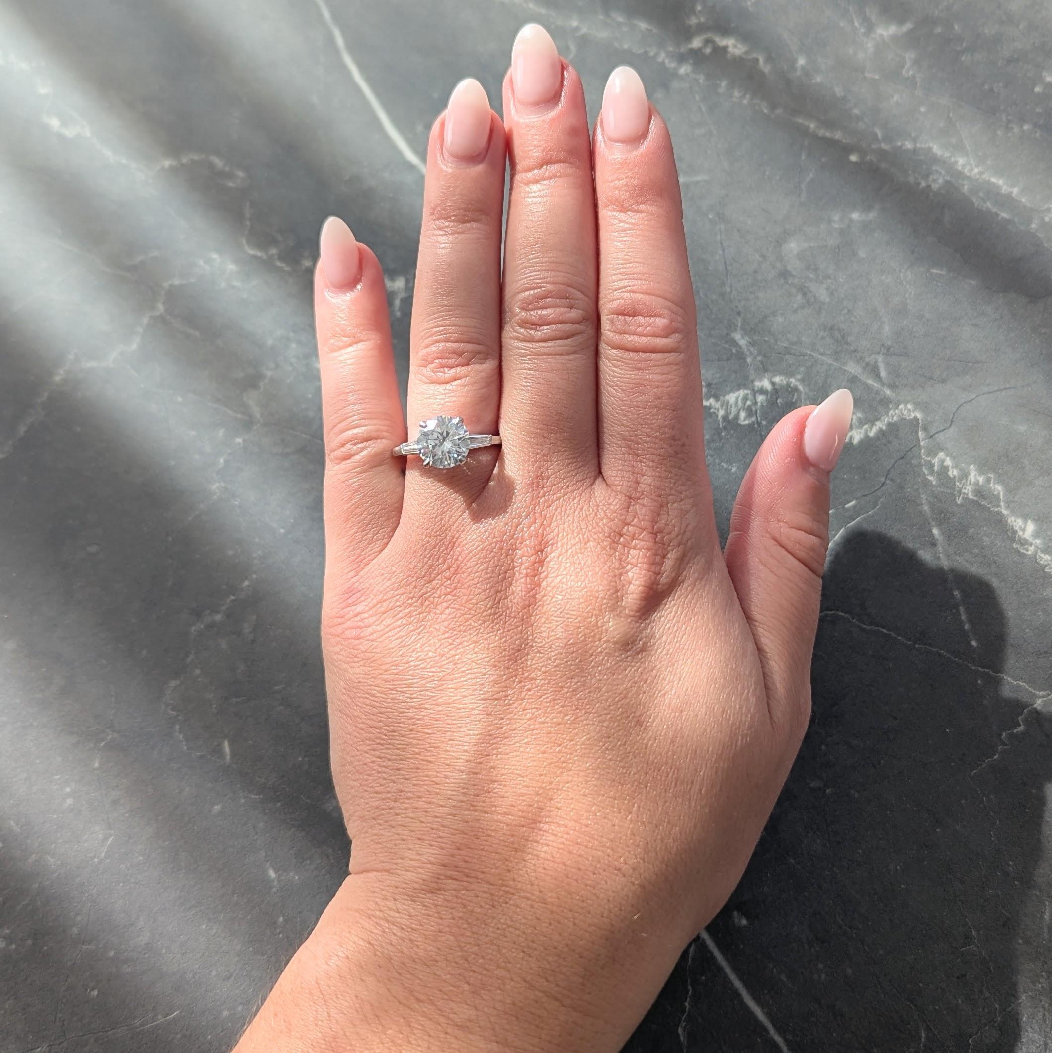 Centrado en un diamante talla brillante redondo de 2,58 quilates - color J con claridad SI2
Engastado en cesta y flanqueado por hombros catedral
Barra engastada con diamantes talla baguette cónicos
Con un peso total aproximado de 0,30 quilates
Bien