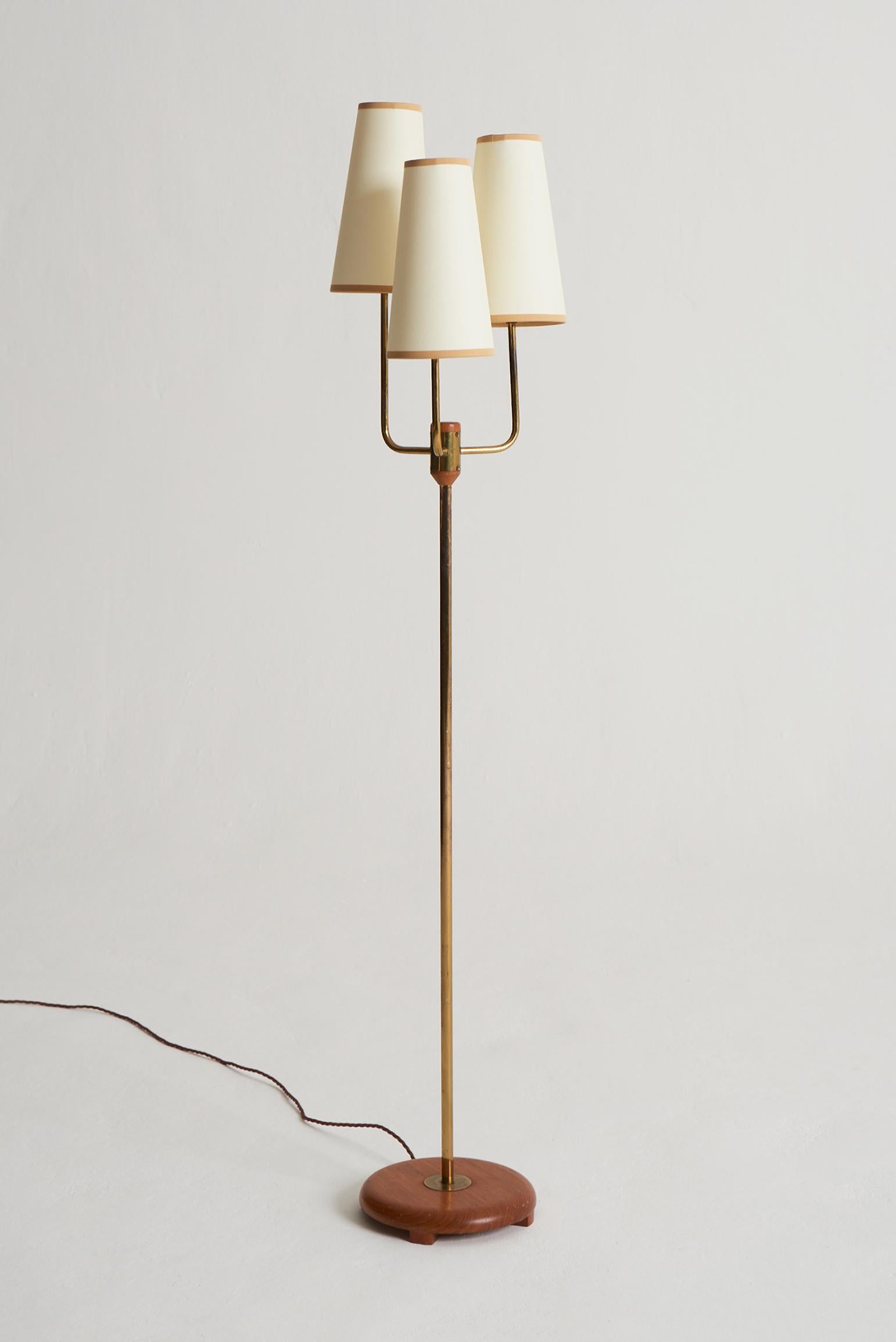 A brass and teak three-armed floor lamp, with bespoke shades.
Sweden, third quarter of the 20th century.