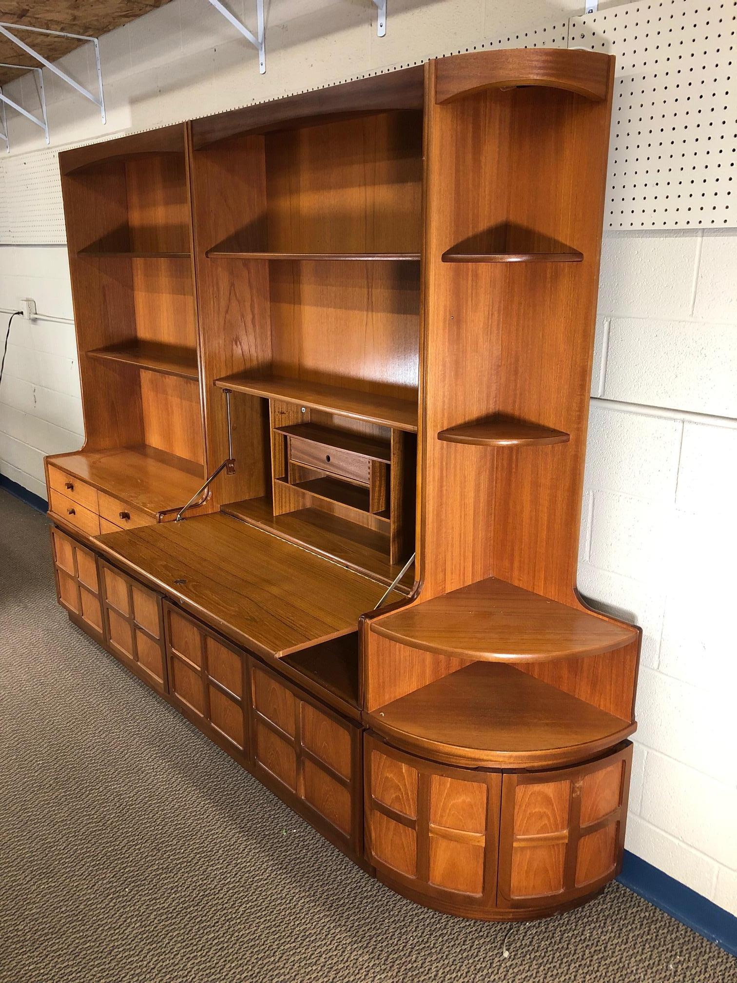 Fantastic teak wall unit made by Nathan Furniture. Made in England.

Features 2 main units and a corner unit. It can be arranged anyway you like it and each piece can also stand by itself. The top shelves are adjustable. The drop down door opens