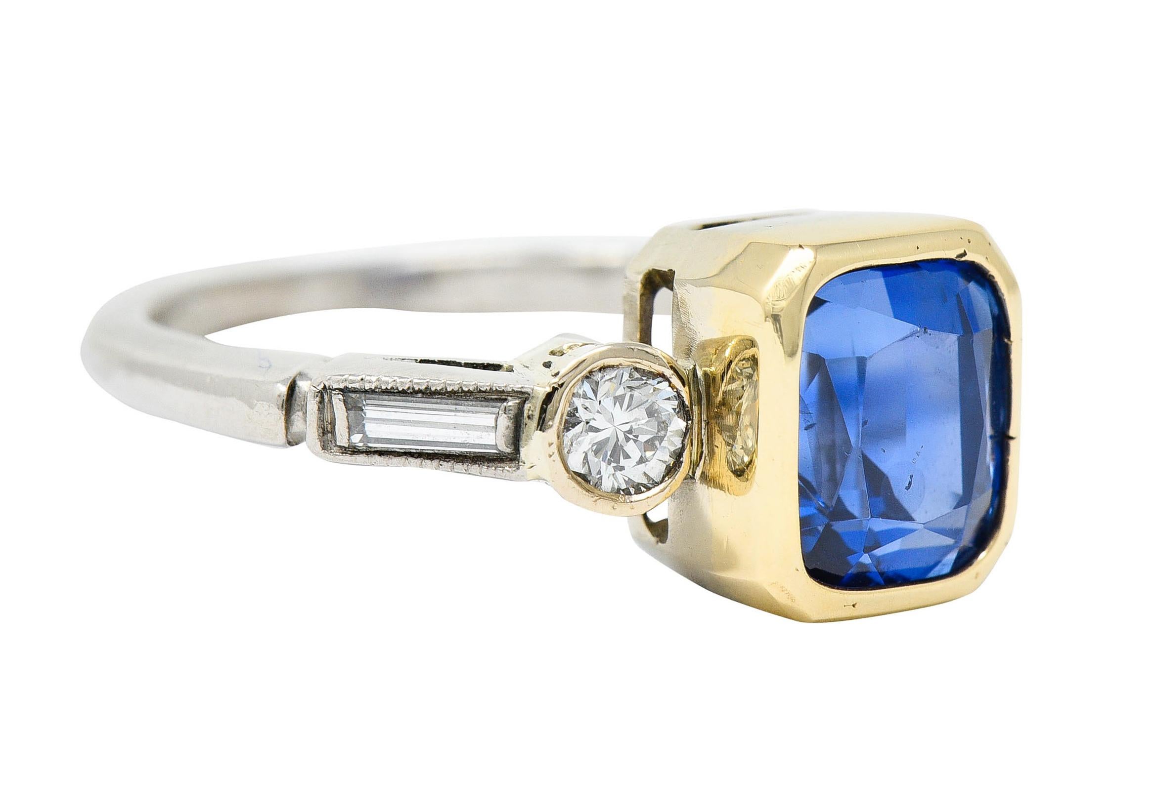 Centering a cushion cut sapphire weighing approximately 3.20 carats

Bright royal blue in color and bezel set in a polished gold surround

Flanked by geometric shoulders featuring bezel set round brilliant and baguette cut diamonds

Weighing in