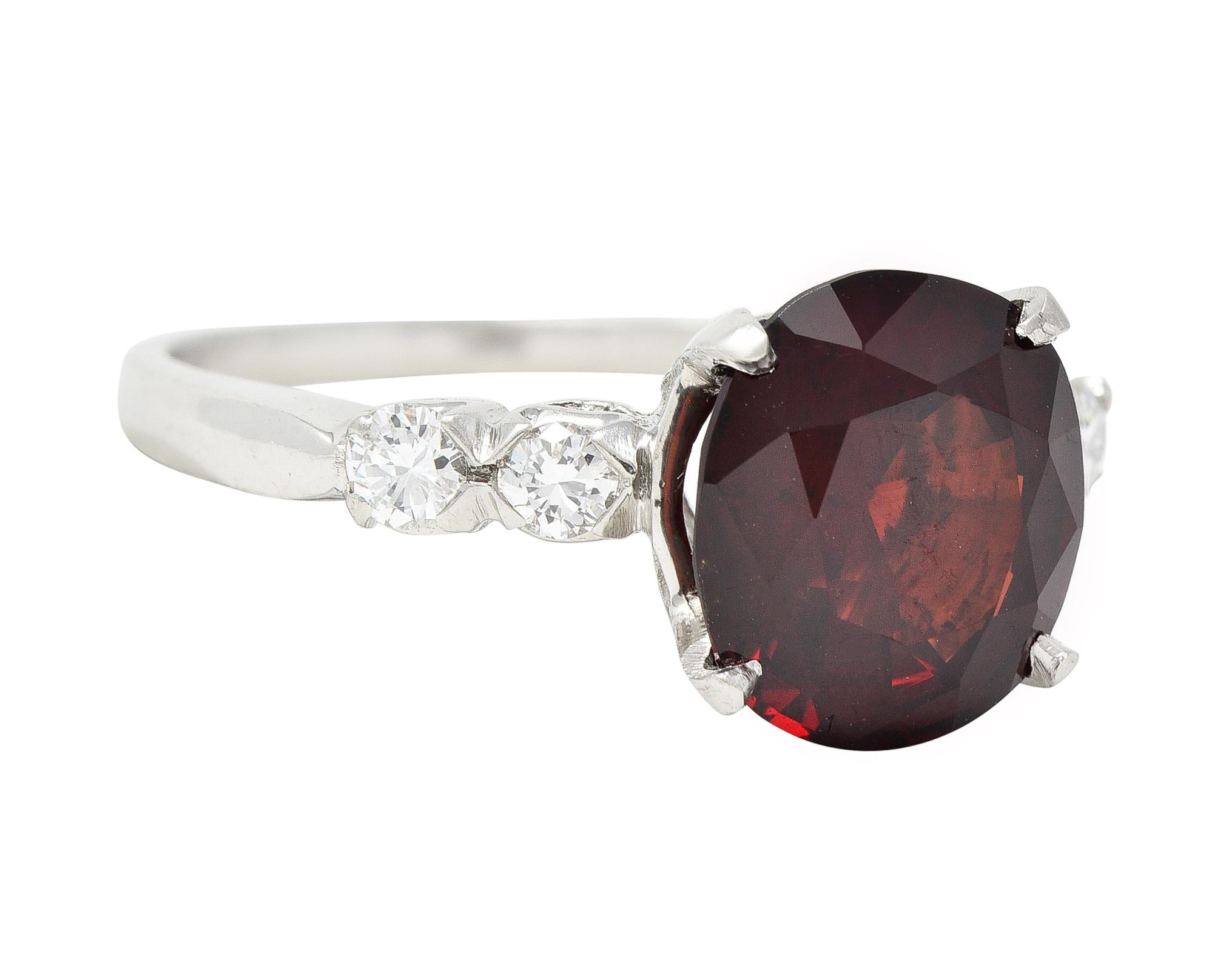 Centering a cushion cut spinel weighing approximately 3.62 carats - transparent dark red in color 
Prong set in basket and flanked by prong set round brilliant cut diamonds
Weighing approximately 0.20 carats total - eye clean and bright
Completed by