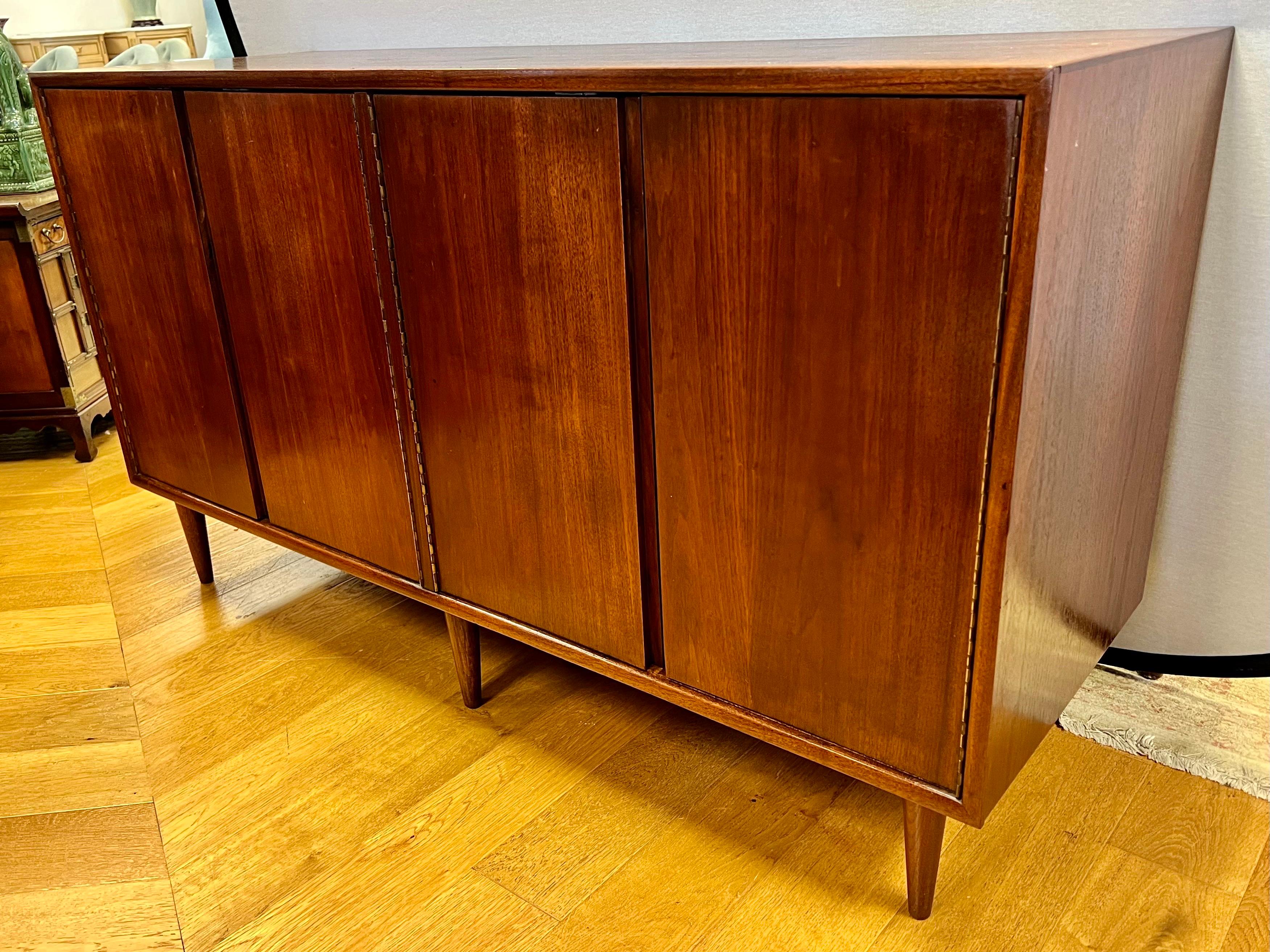 Mid century four door entertainment console has beautiful walnut graining. Left side double doors open to record cubbies and shelving for the vinyl collector! Right side door open to more storage. It has recently been polished to bring out walnut