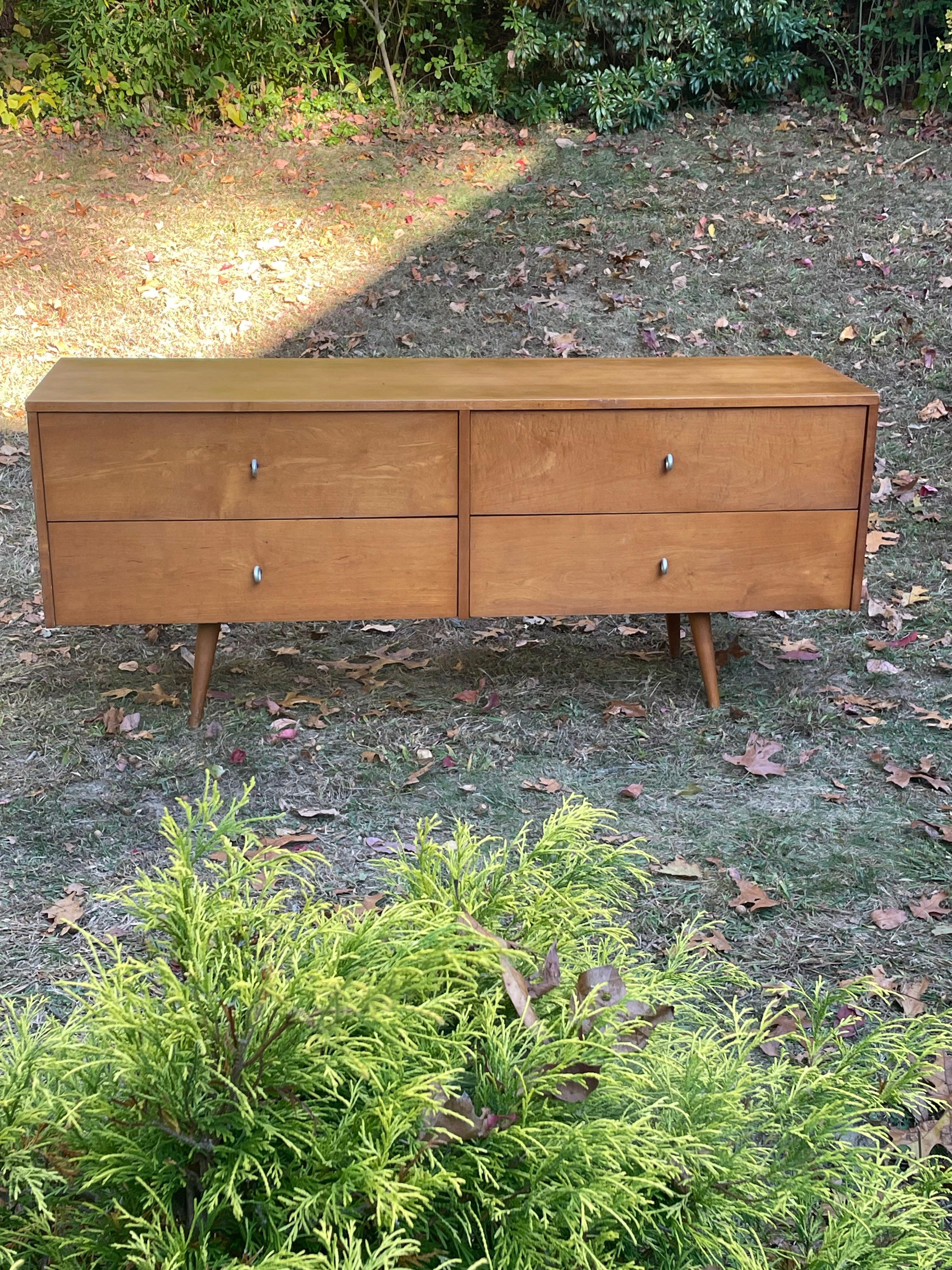 La rara cómoda/credenza Paul McCobb de 4 cajones es de madera maciza de arce con tiradores metálicos circulares de aluminio originales y patas cónicas de arce. Esta pieza forma parte del McCobb Planner Group . Circa 1950s. Quemado en la firma