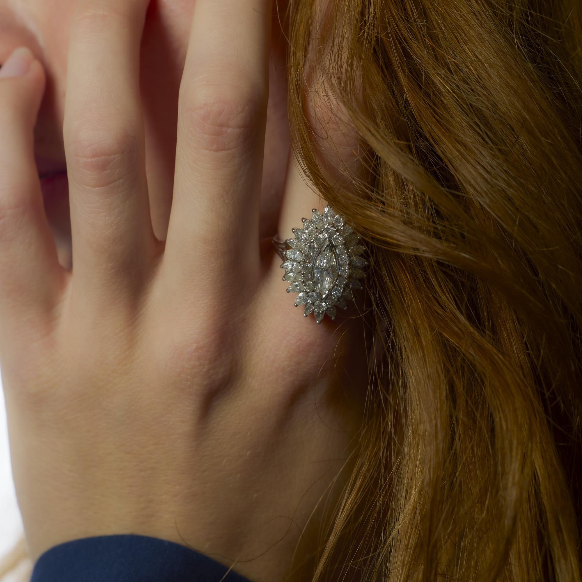 Questo anello in platino di metà secolo mette in mostra un sorprendente diamante marquise da 0,90 carati circondato da 3,40 carati di accenti scintillanti in un design scultoreo e glamour.