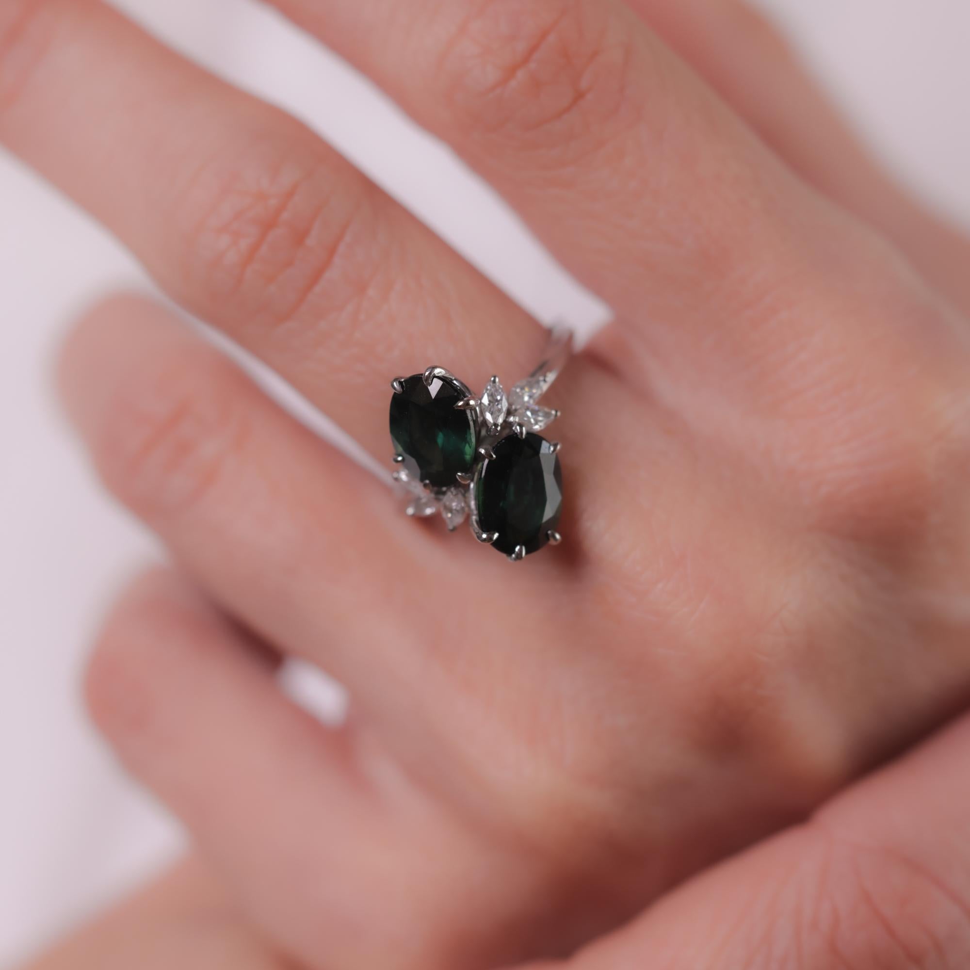 This mid-century platinum ring features two oval-cut green sapphires totaling 4.34 carats, accented by six marquise-cut diamonds totaling approximately 0.40 carats, E-F color, VS clarity. Circa 1950s.

Center stone: 2 oval cut green
