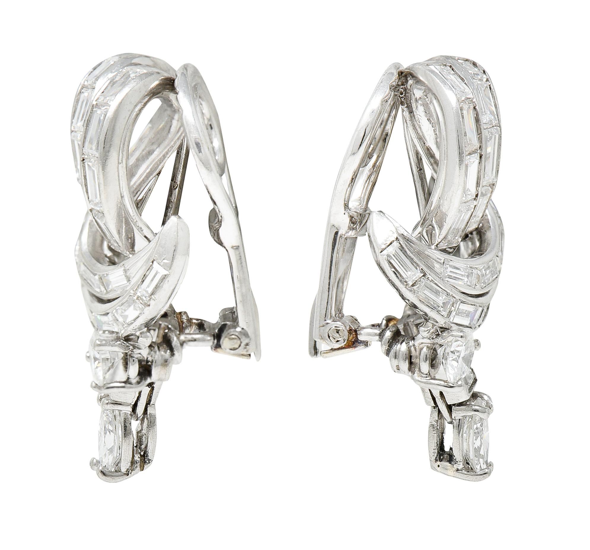 Ear-clips are designed as a scrolling loop form with articulated basket set diamond drops

Channel set throughout by baguette cut diamonds and accented by marquise and round brilliant cut diamonds

Weighing in total approximately 4.50 carats with G