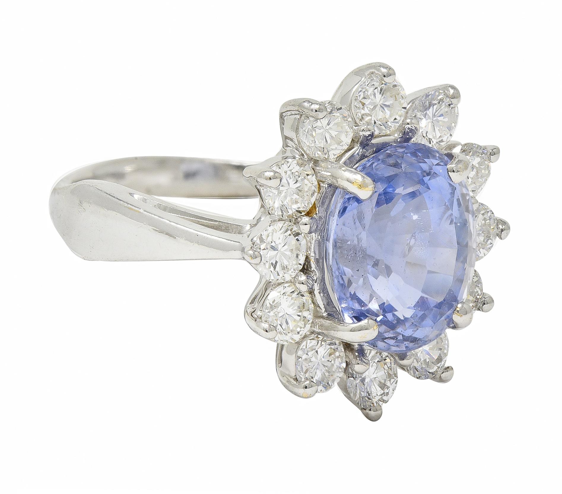 Centering an oval step cut sapphire weighing approximately 3.79 carats total 
Natural with no indications of heat treatment - transparent light blue
Prong set with a halo surround of round brilliant cut diamonds
Weighing approximately 1.70 carats