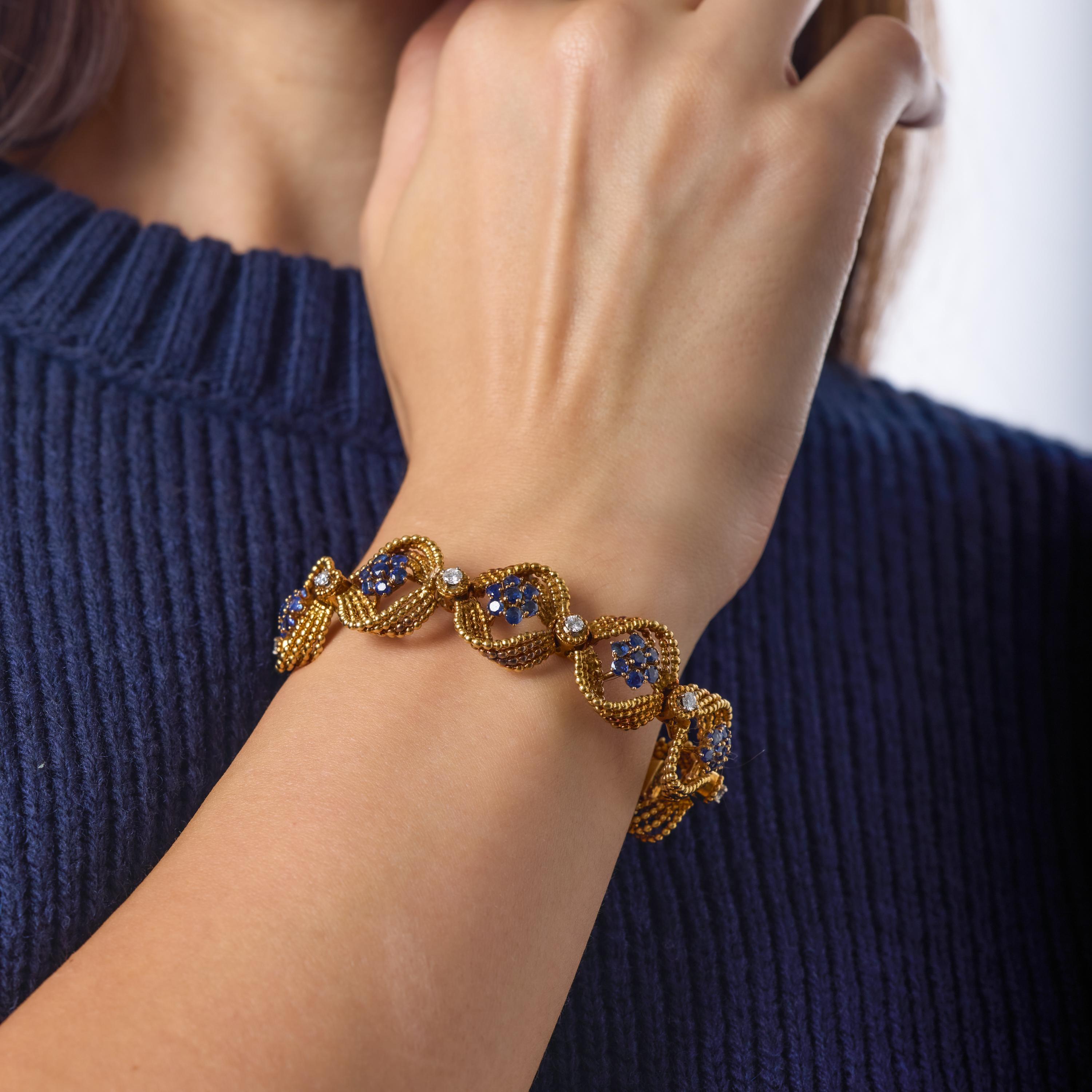 Esta llamativa pulsera de mediados de siglo muestra un atrevido diseño de oro retorcido iluminado por vibrantes zafiros azules que envuelven con gracia la muñeca. Los zafiros de ricos colores se acentúan con brillantes diamantes redondos que añaden