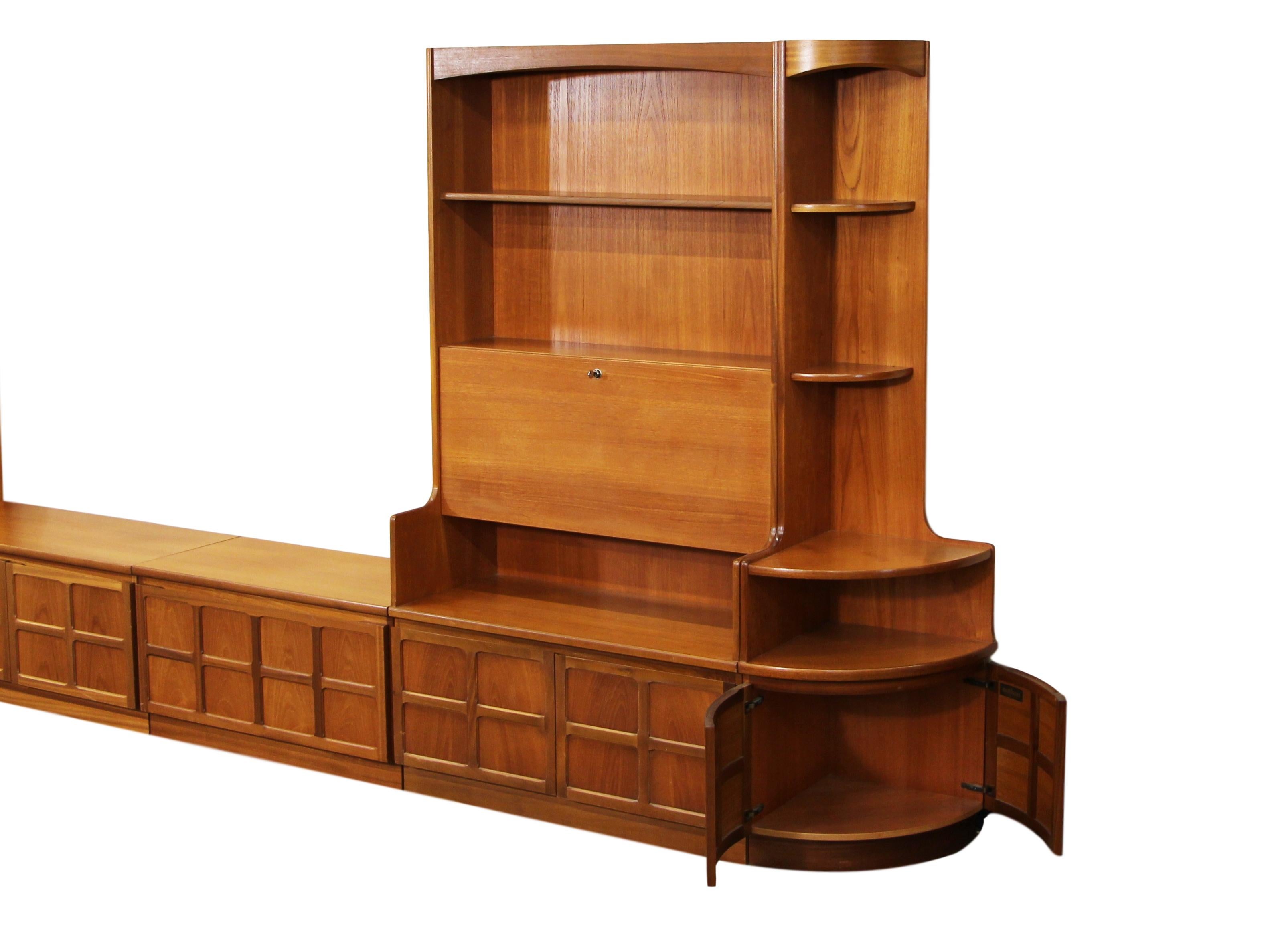 Fantastic teak wall unit made by Nathan Furniture. Made in England.

Features a tall glass door unit, a tall drop down door unit with functioning lock and key, a lower 2 door cabinet and a lower drop down door cabinet with sliding shelf to house