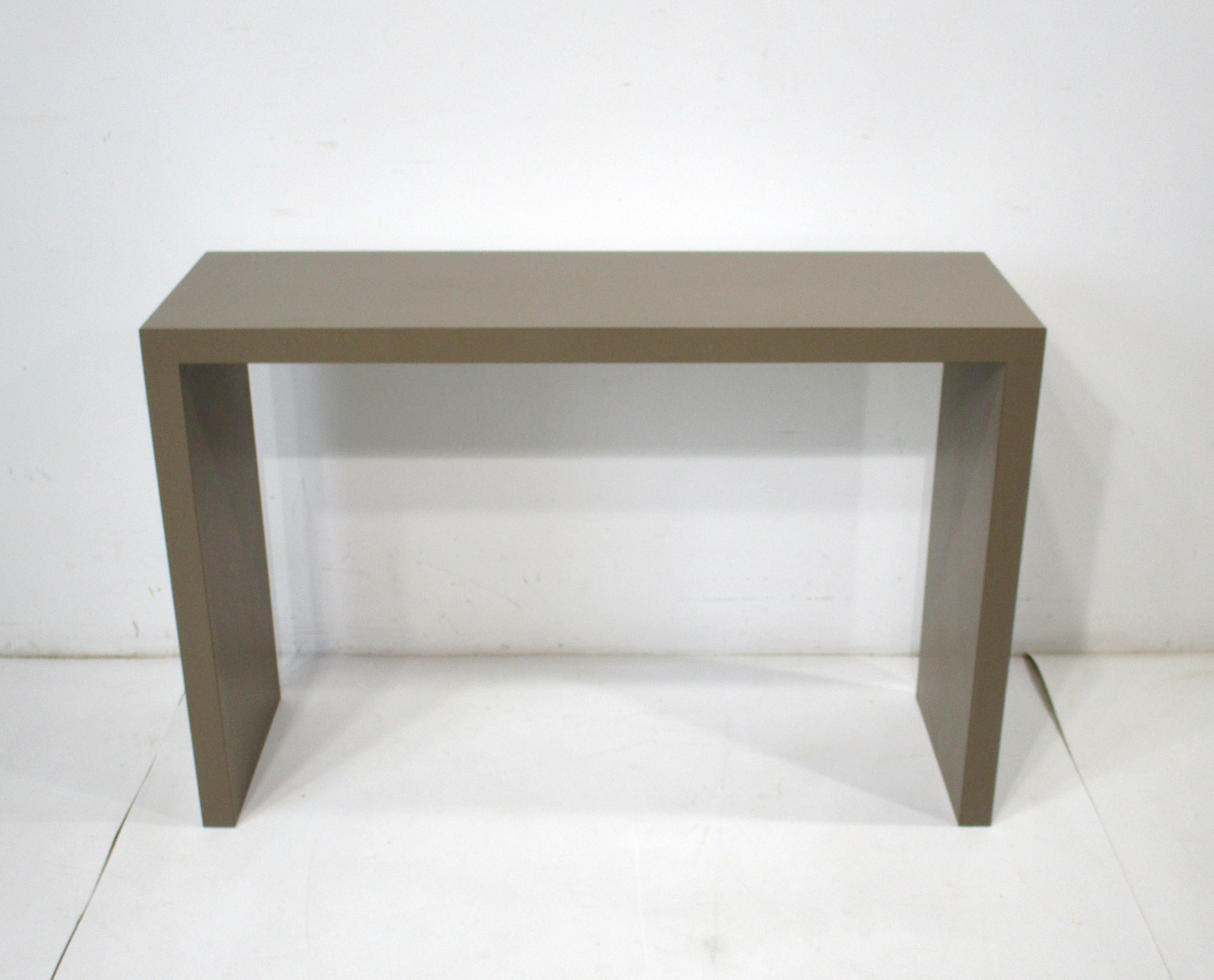 A nice slab sided console table in a medium taupe laminate , this clean simple form will work with any interior or style . The perfect piece for an entrance way , end of a hall , office or behind a sofa . 
