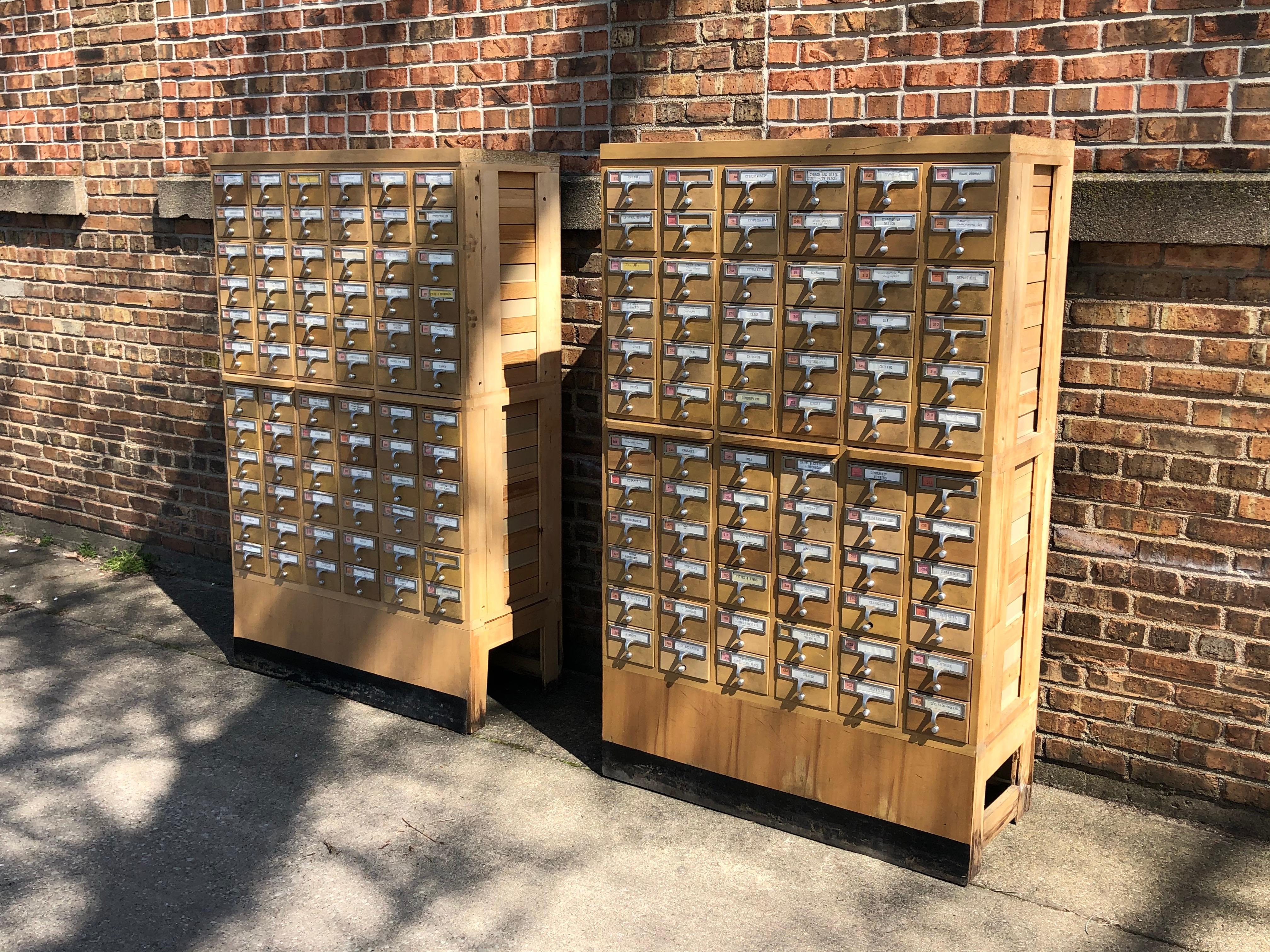A rare pair of midcentury library card catalog cabinets procured from the library at Western Michigan University. The card catalogs feature beautiful wood grain and an amazing 72 dovetailed drawers. All of the drawers slide well, and they have