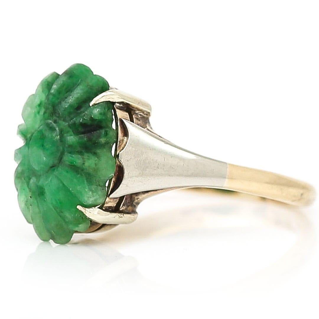 A pretty, 9ct bicolour gold carved jadeite floral cabochon statement ring. The ring dating from circa 1960 has a masterfully carved, claw set deep green jadeite flower head at its centre. The shank has been crafted from yellow and white gold.