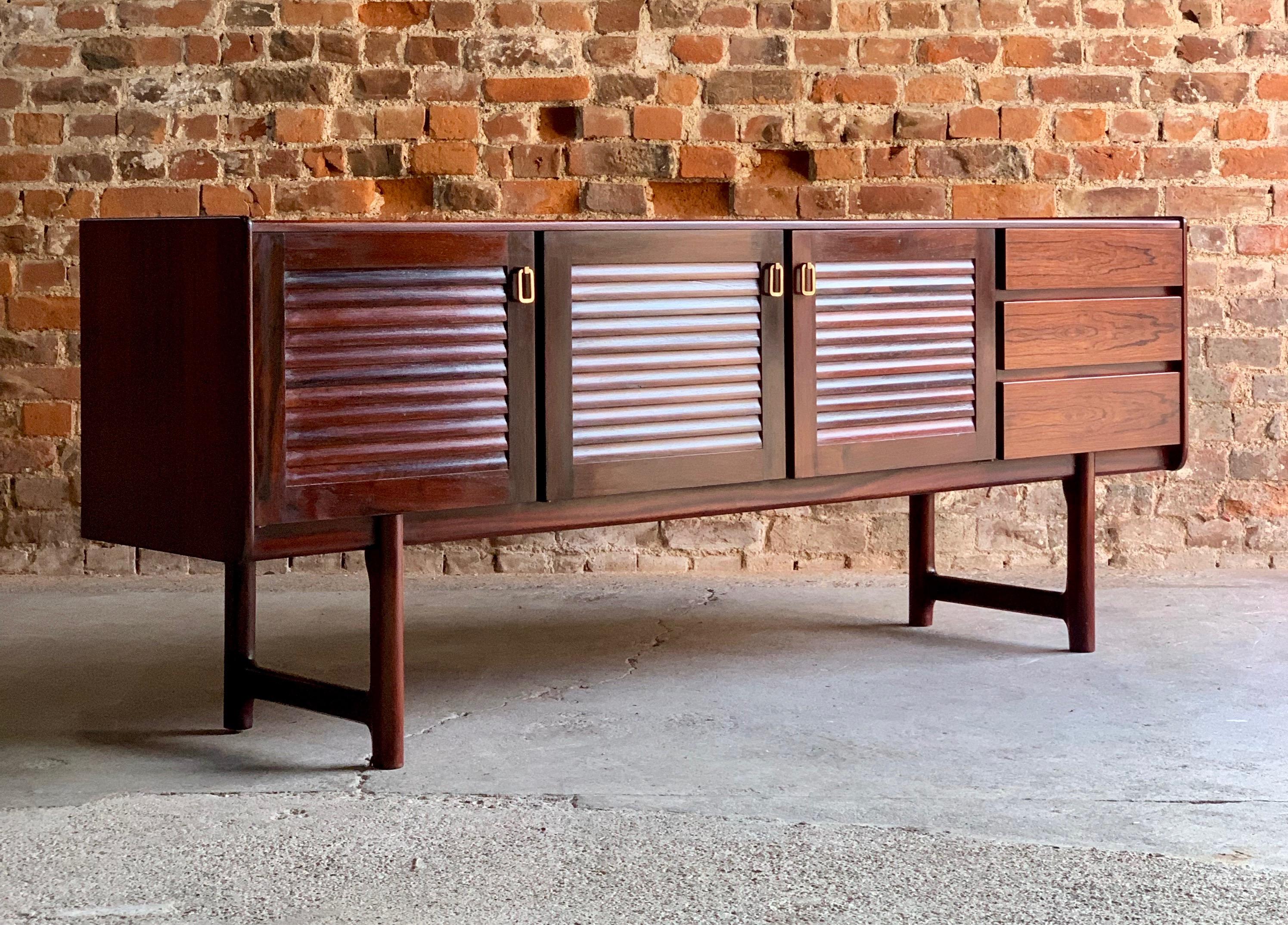 Magnificent midcentury A. H. McIntosh & Co of Kirkcaldy rosewood sideboard credenza, circa 1970s, the rectangular top over three louvered cupboard doors with brass handles and shelves within, three drawers to the right side and raised one four