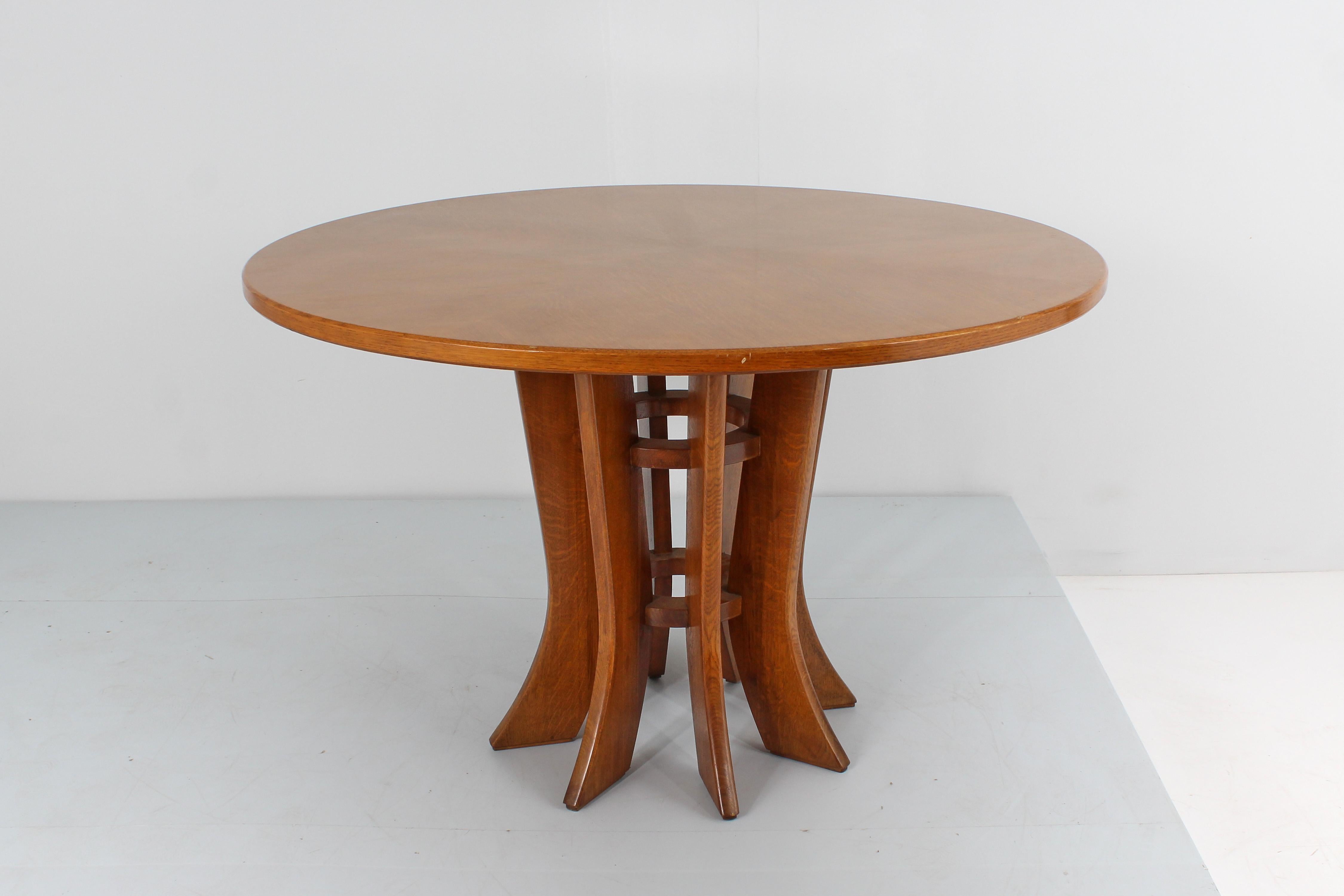 Beautiful round wooden dining table with an elegant central pedestal made up of shaped and rounded slats, positioned in a radial pattern, connected by two wooden ring bands, to create an open structure. In the style of Angelo Mangiarotti, Italian