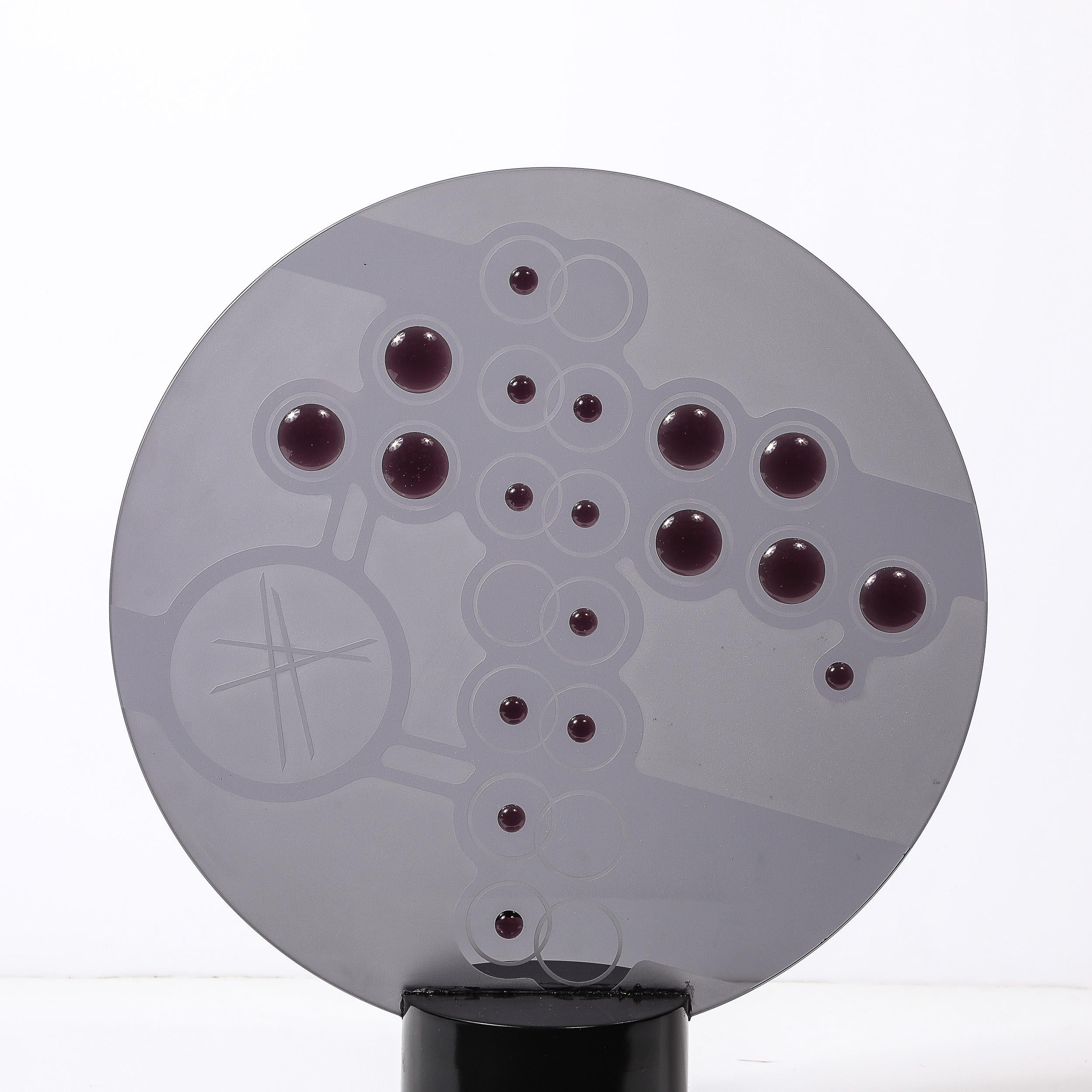 This captivating Mid-Century Modernist sculpture merges sleek design with artistic sophistication. Featuring a striking smoked glass disc, the sculpture is adorned with frosted detailing that radiates an abstract, ethereal quality. Adding a bold,