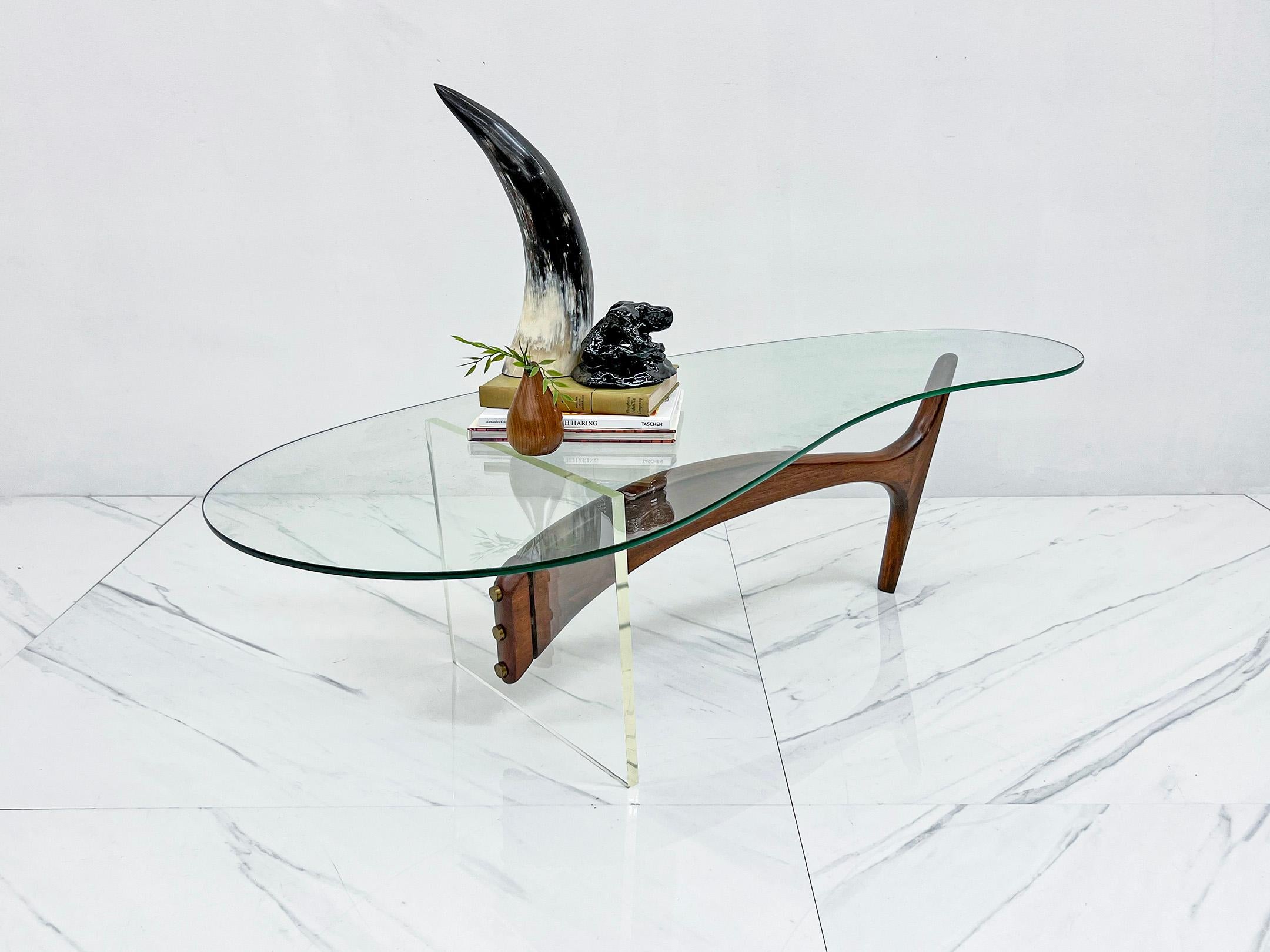 This coffee table is stunning! Composed of an angular sleek walnut leg that is split at the end by a thick clear acrylic leg, and mounted on with brass hardware. 

This captivating mid-century modern coffee table that seamlessly blends organic