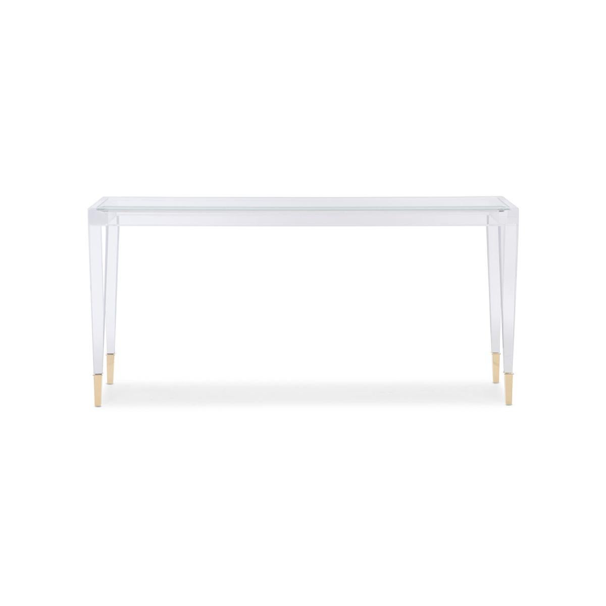 With a clear acrylic frame, its see-through design adds modern charm to a room while still feeling visually light and airy.

The rectangular shape with inset clear glass top, above square tapered legs with metal ferrules in Whisper of Gold cap its