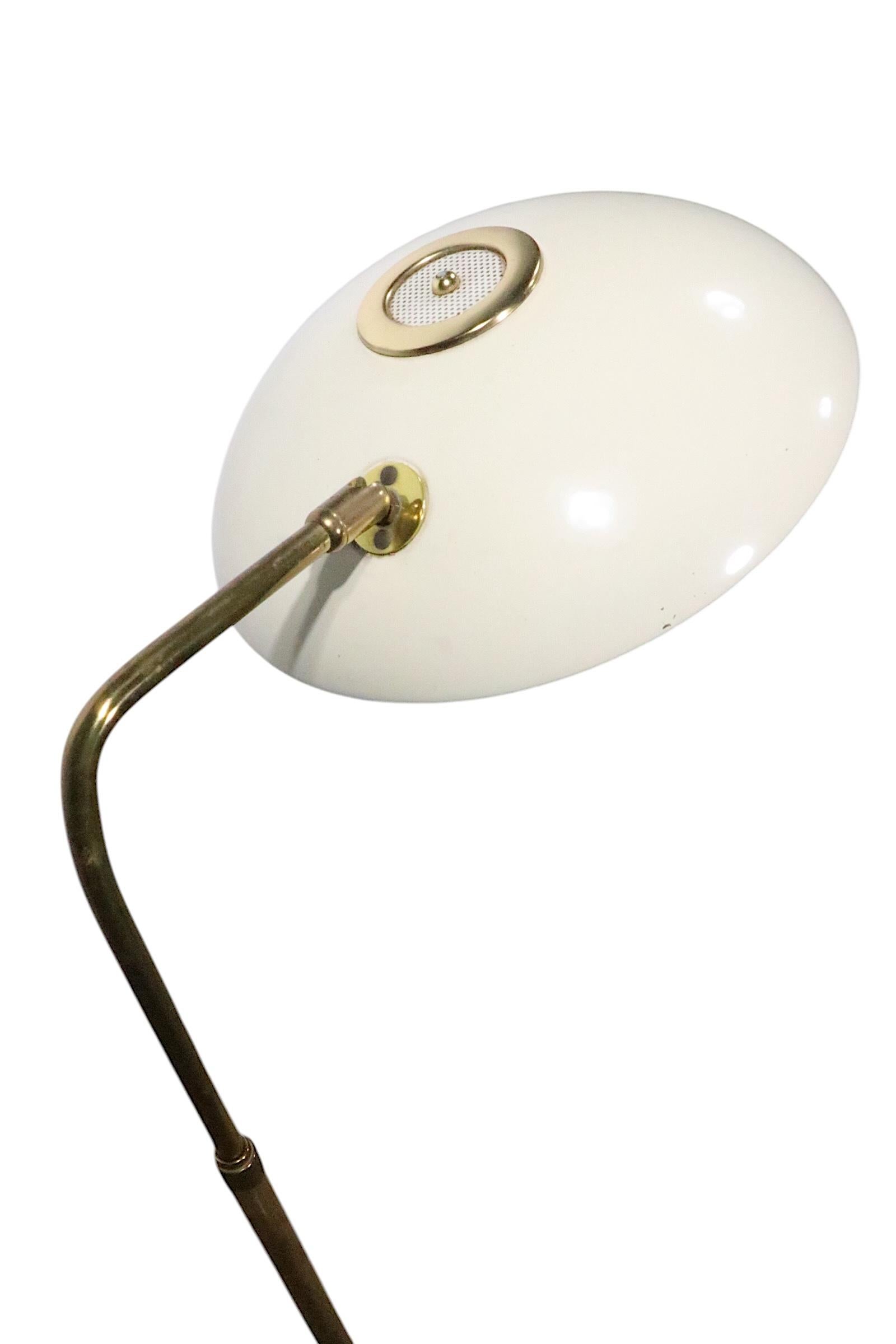 Icónica lámpara de pie de mediados de siglo, diseñada por Gerald Thurston para Lightolier, hacia la década de 1950.  La lámpara tiene una pantalla ajustable en forma de platillo, con un brazo de latón y una base en forma de disco. La lámpara tiene