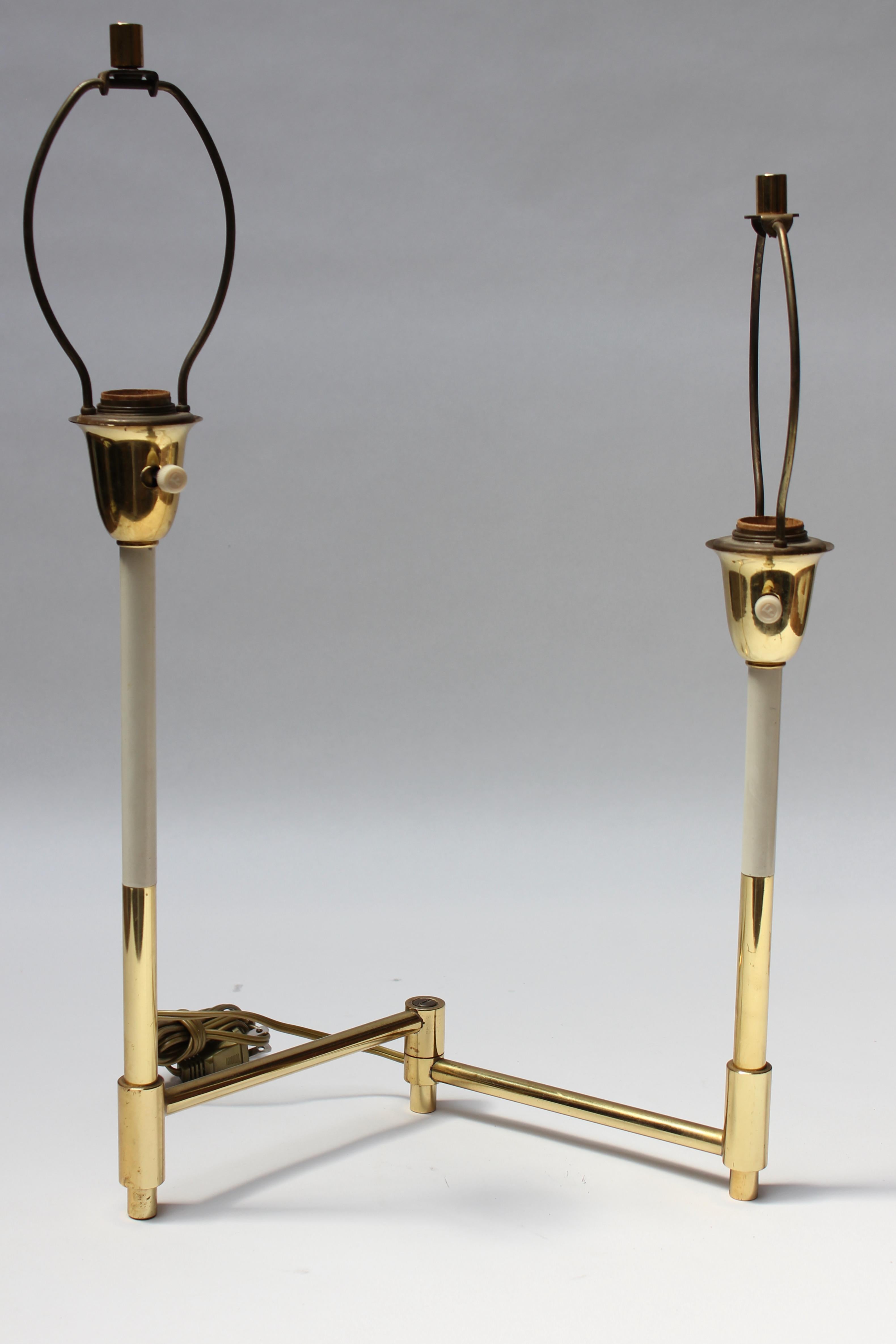 Uncommon Laurel pivoting two fixture brass and off-white painted metal table lamp. The stems splay apart in an accordion style, and the length can be extended from 4.25