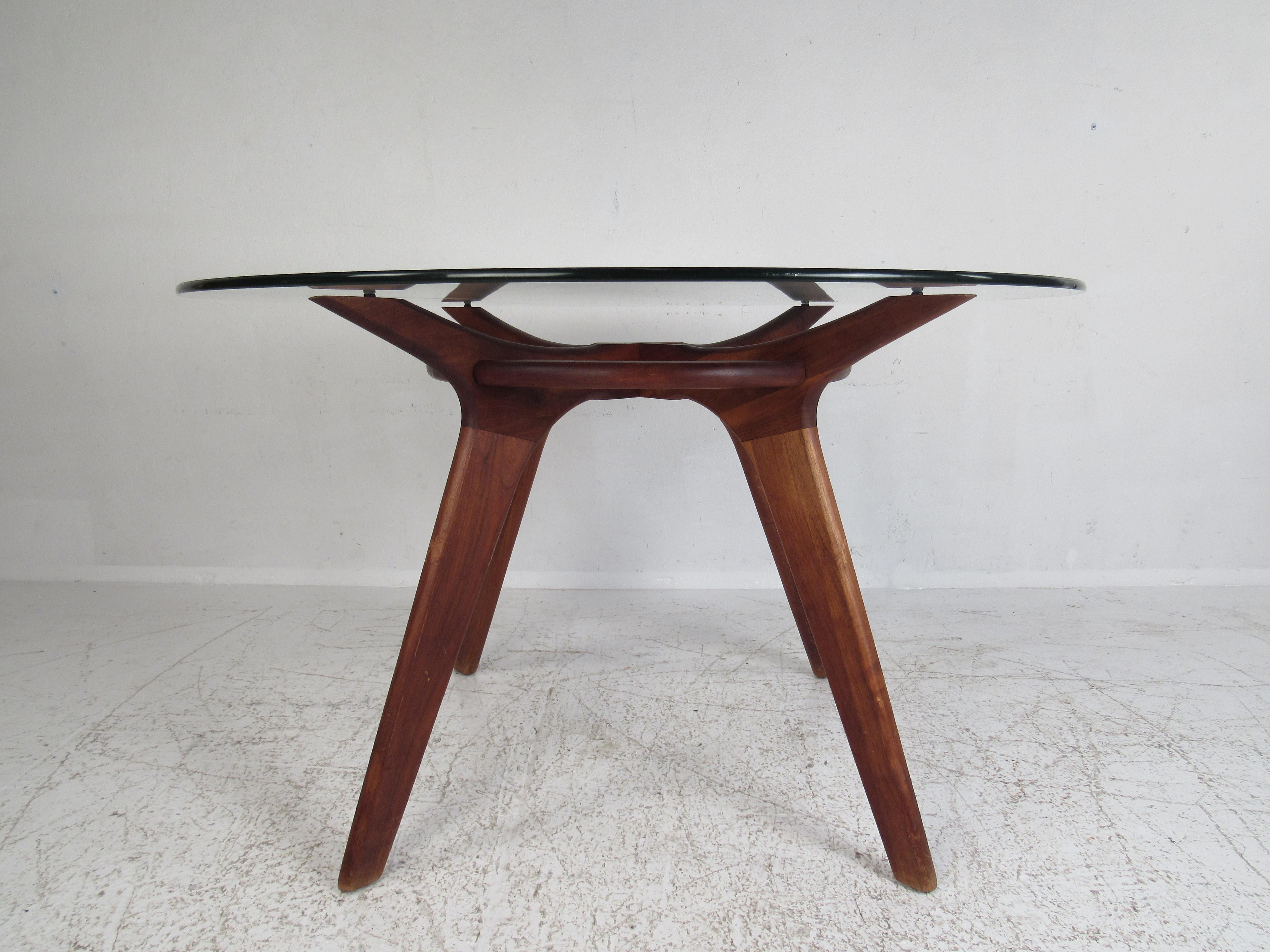 A spectacular vintage design by Adrian Pearsall with a large round glass top and a sculpted walnut base. This stunning mid-century table resembles a compass, hence the name. The elegant walnut wood grain, angled legs, and sculpted top supports add