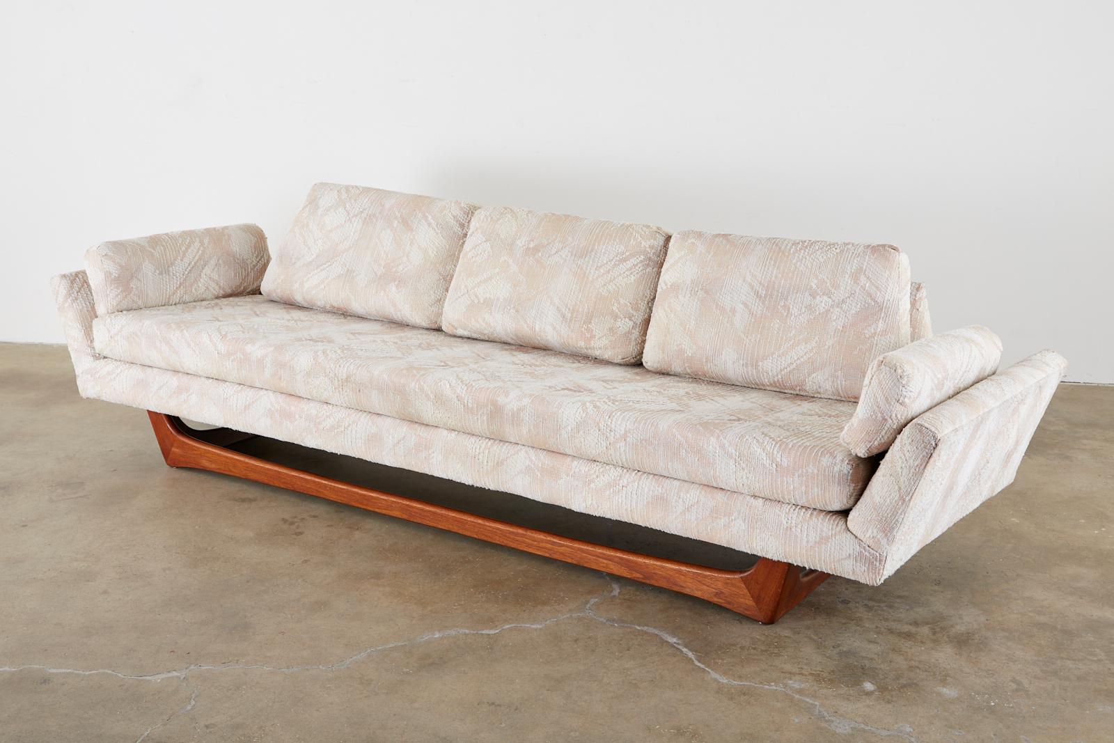 Large Mid-Century Modern gondola sofa attributed to Adrian Pearsall for Craft Associates. Features an angular case with distinctive canted arms at each end, and a low sleek profile. Fitted with loose seat cushions and supported by a richly finished