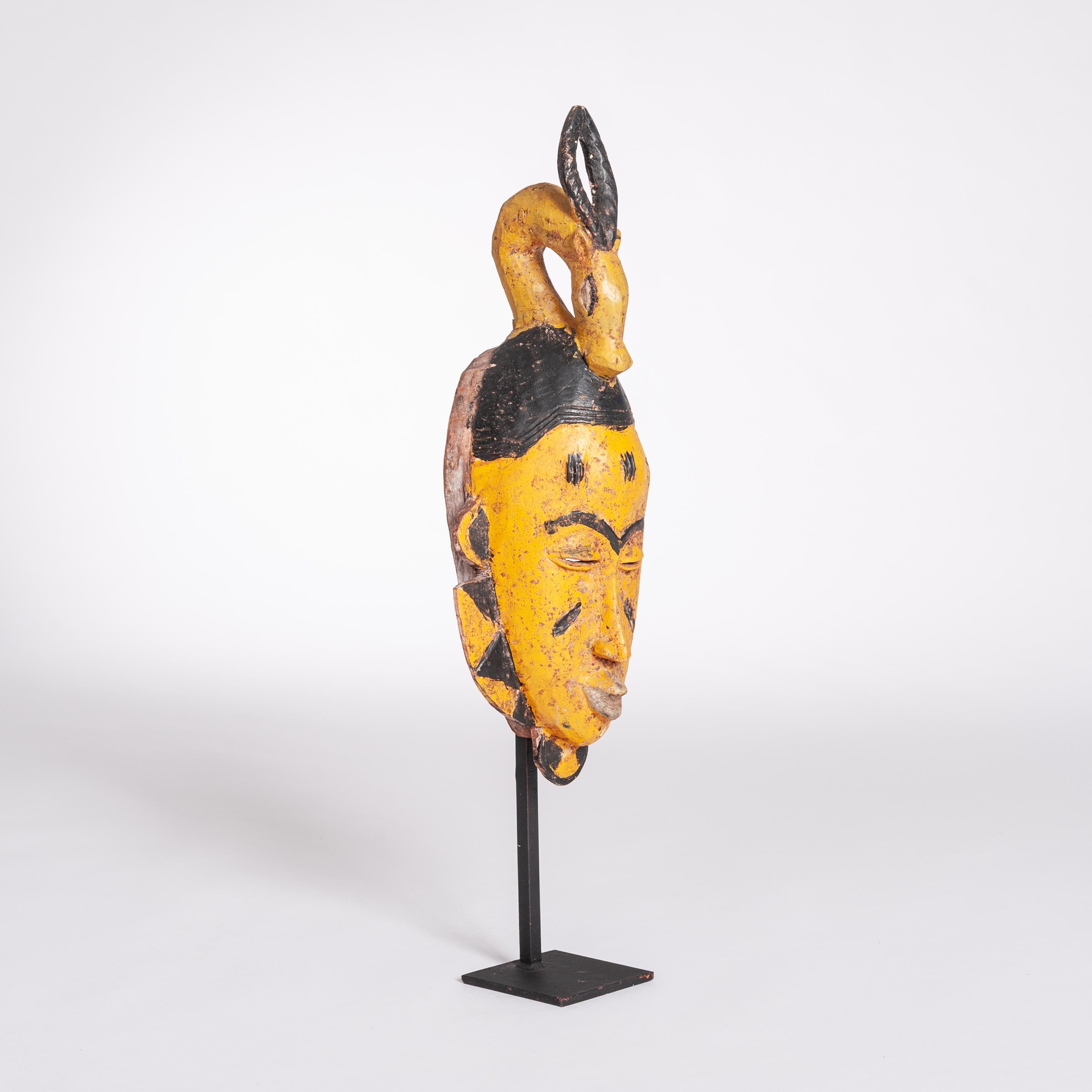 Gelb-schwarze Baoule-Stammesmaske aus der Jahrhundertmitte mit Antilopenkopfverzierung (Holz) im Angebot