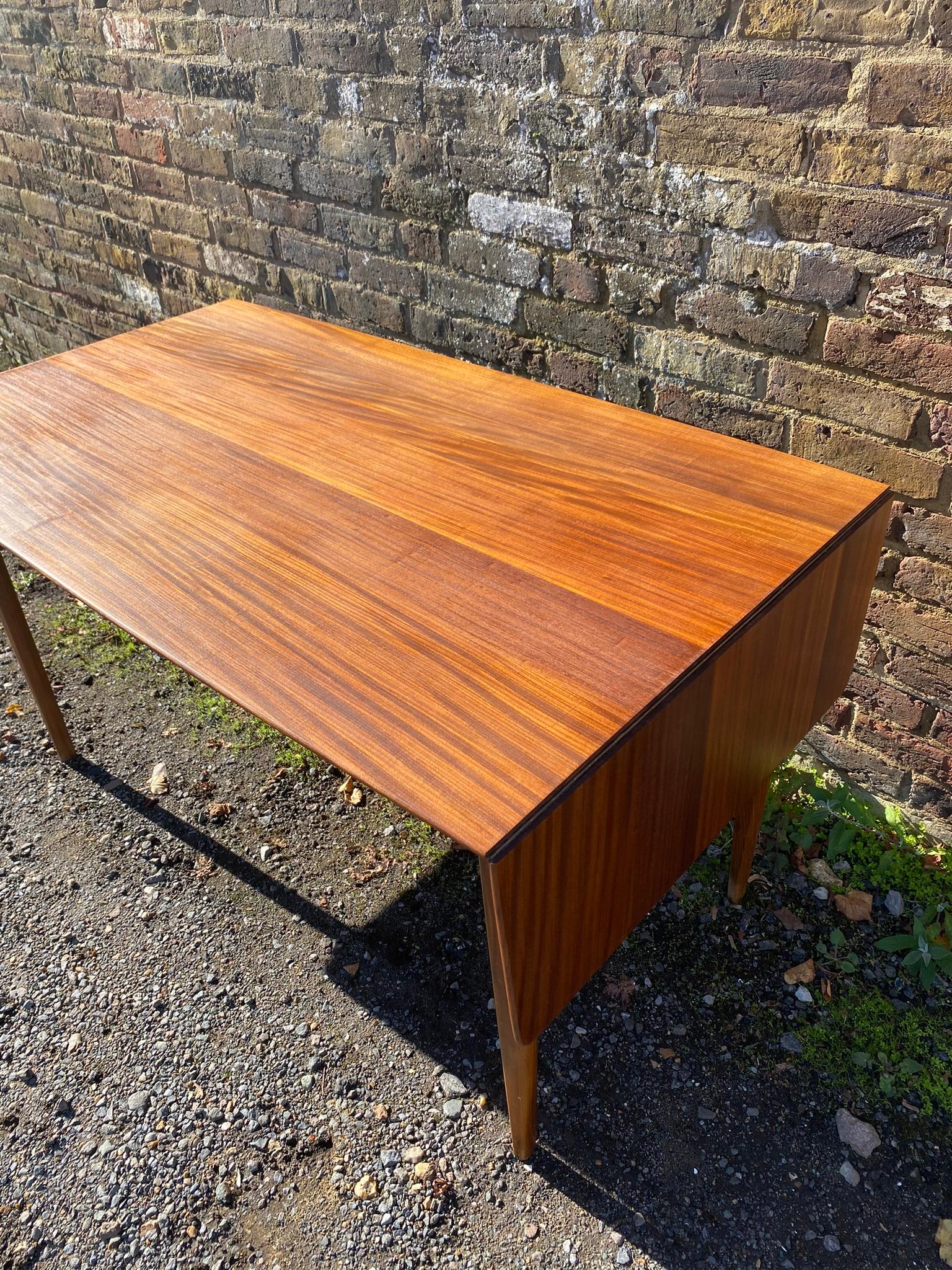 Mid-Century Afromosia Teak Drop-Leaf Dining Table, Denmark, 1960s

The mid-century afromosia teak drop-leaf dining table from Denmark in the 1960s is a striking representation of the elegant and functional design characteristic of the era. Crafted