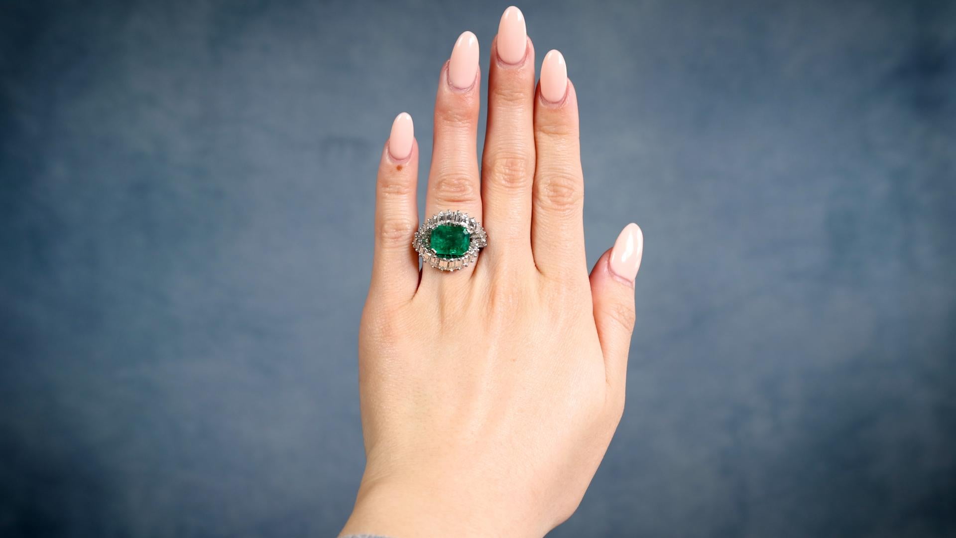 One Mid-Century AGL Colombian Minor Oil Emerald Diamond Cocktail Ring. Featuring one AGL octagonal cut emerald weighing 3.72 carats, accompanied by AGL #1138263 stating the Colombian origin with minor oil treatments. Accented by 26 baguette cut
