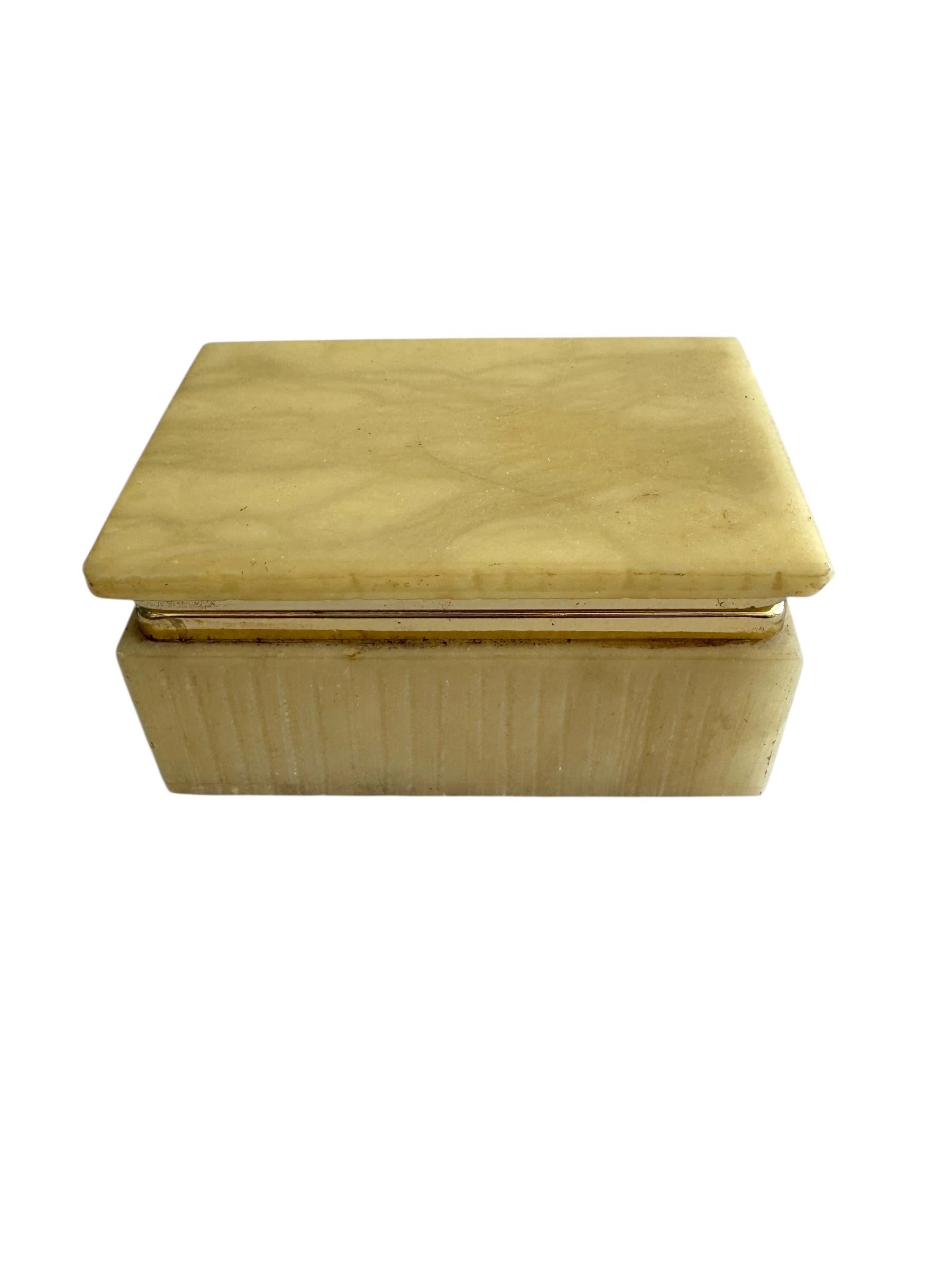 A refined mid-century alabaster box, expertly carved from solid stone with natural veining in soft, muted tones. The smooth, polished surface and clean lines highlight the beauty of the material, while the hinged lid opens to reveal storage for