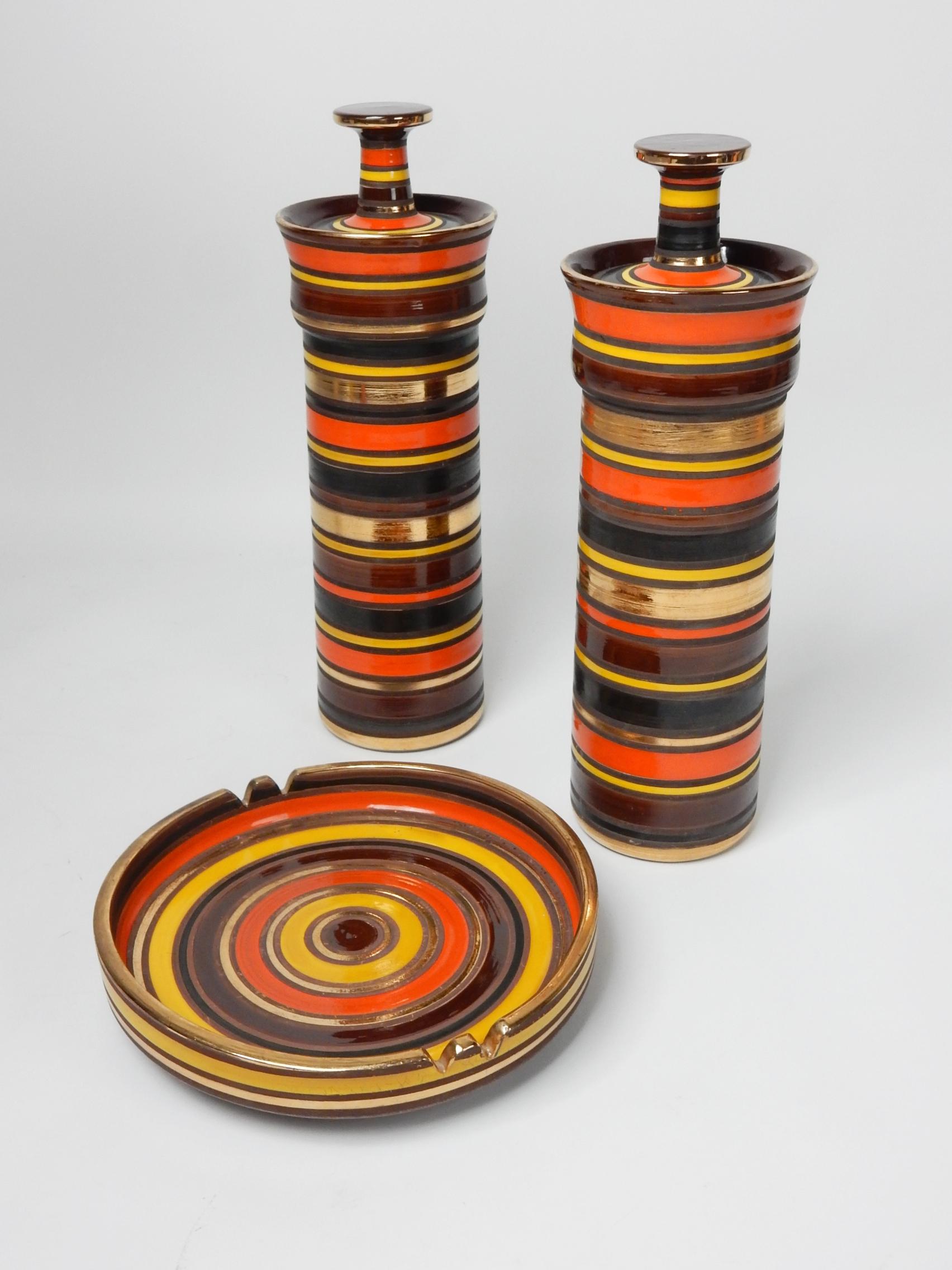Incredible set by Aldo Londi for Raymor Italy 1950's.
A large pair of lidded jars standing 16 inches tall x 5-1/2 wide.
Large ashtray is 10-1/2 inches wide x 2 inch tall sides.
Bright bold colored glaze bands of orange, yellow, gold black and