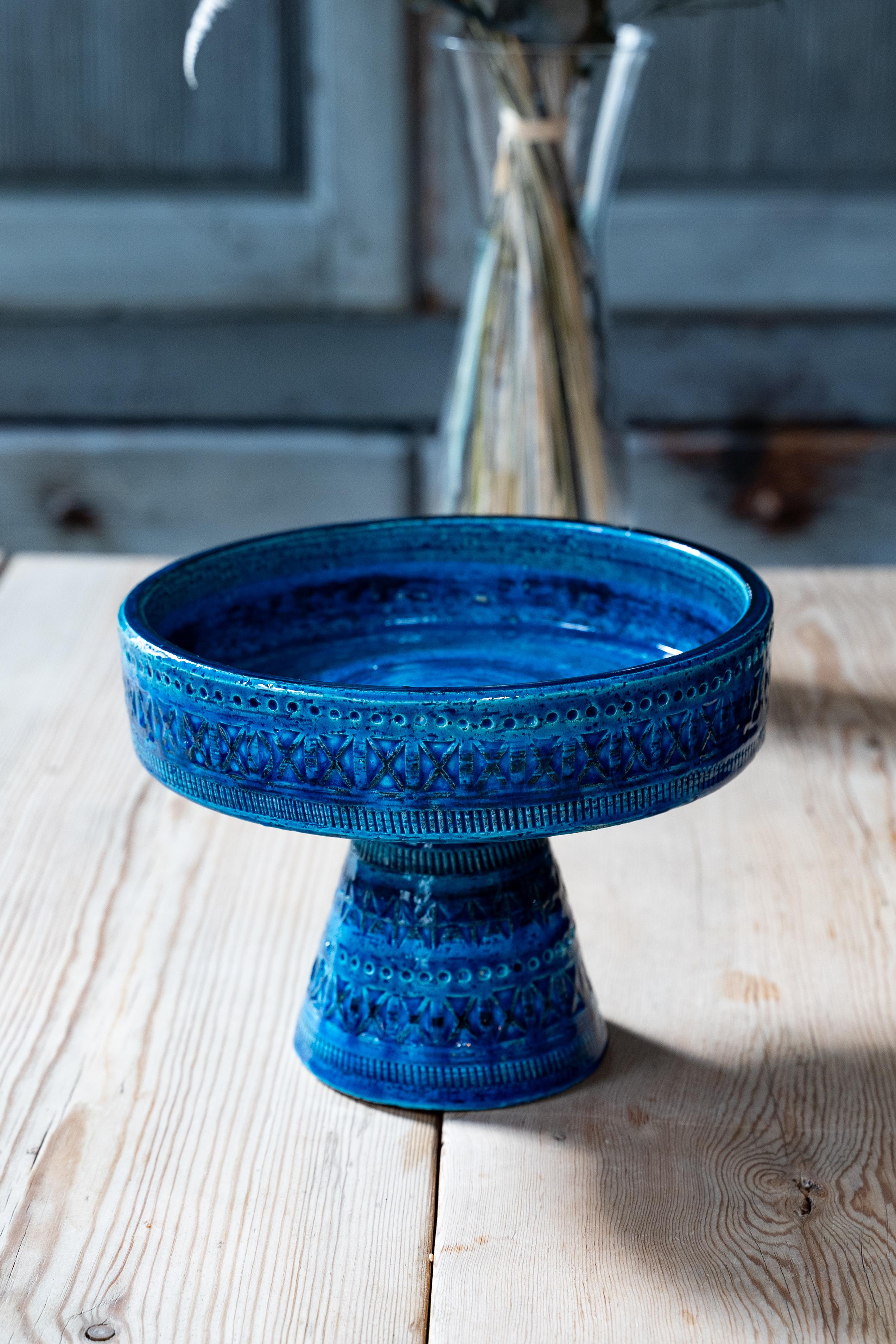 Este cuenco con pedestal vintage de la icónica colección Rimini Blue de Bitossi es una obra maestra del diseño cerámico italiano de mediados de siglo. Con su vibrante esmalte cobalto y sus intrincados motivos geométricos tallados a mano, esta pieza