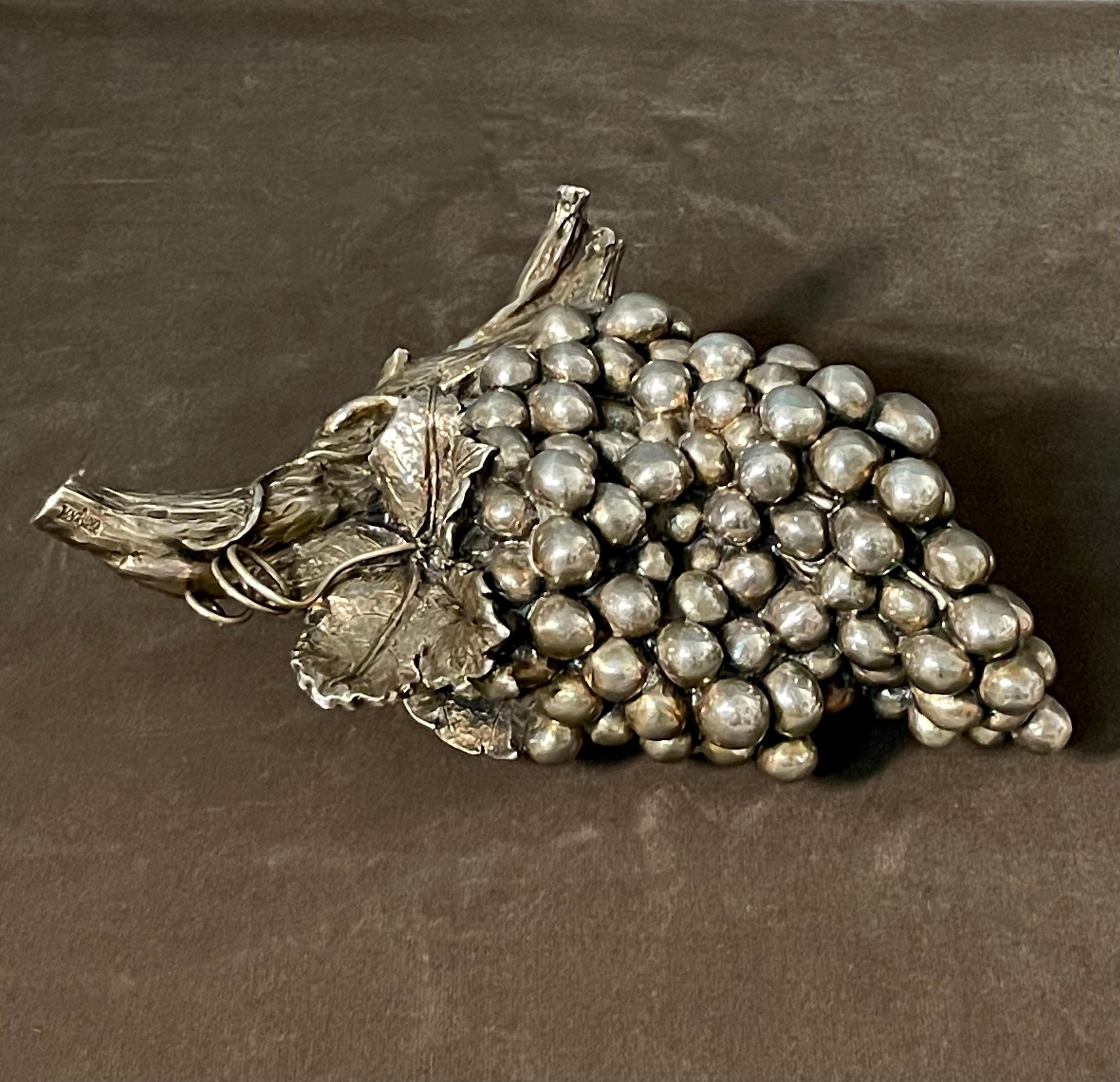 Un bellissimo ed esclusivo oggetto di design italiano degli anni '50, creato dal famoso designer e argentiere Alessandro Magrino.
Eleganza e laminazione in argento di grado 1000, raffigurano un elegante grappolo d'uva ancora appeso alla vite con una