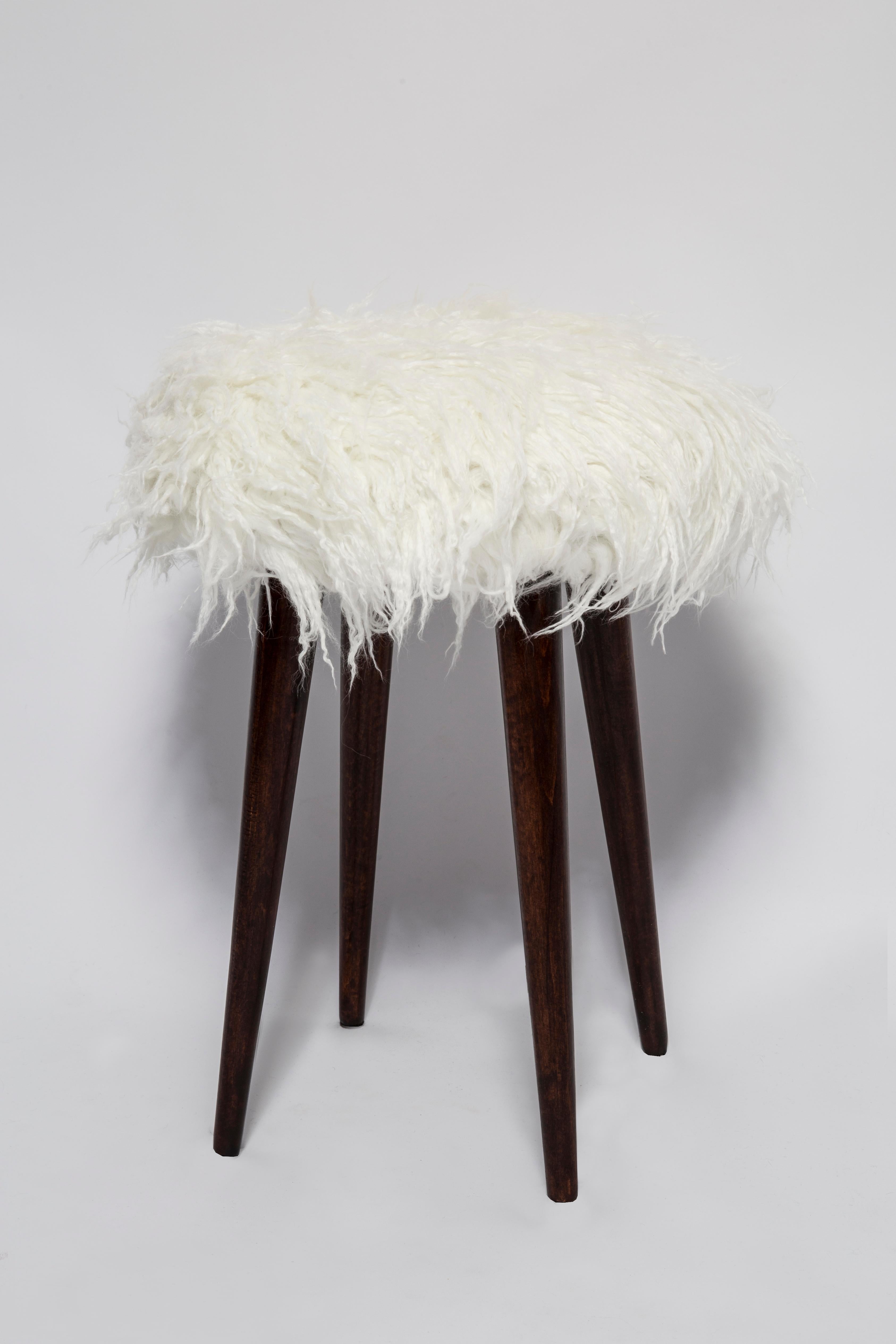 Stool from the turn of the 1960s and 1970s. 

Beautiful white faux fur white upholstery. 

The stool consists of an upholstered part, a seat and wooden legs narrowing downwards, characteristic of the 1960s style. 

We can prepare this stool also in