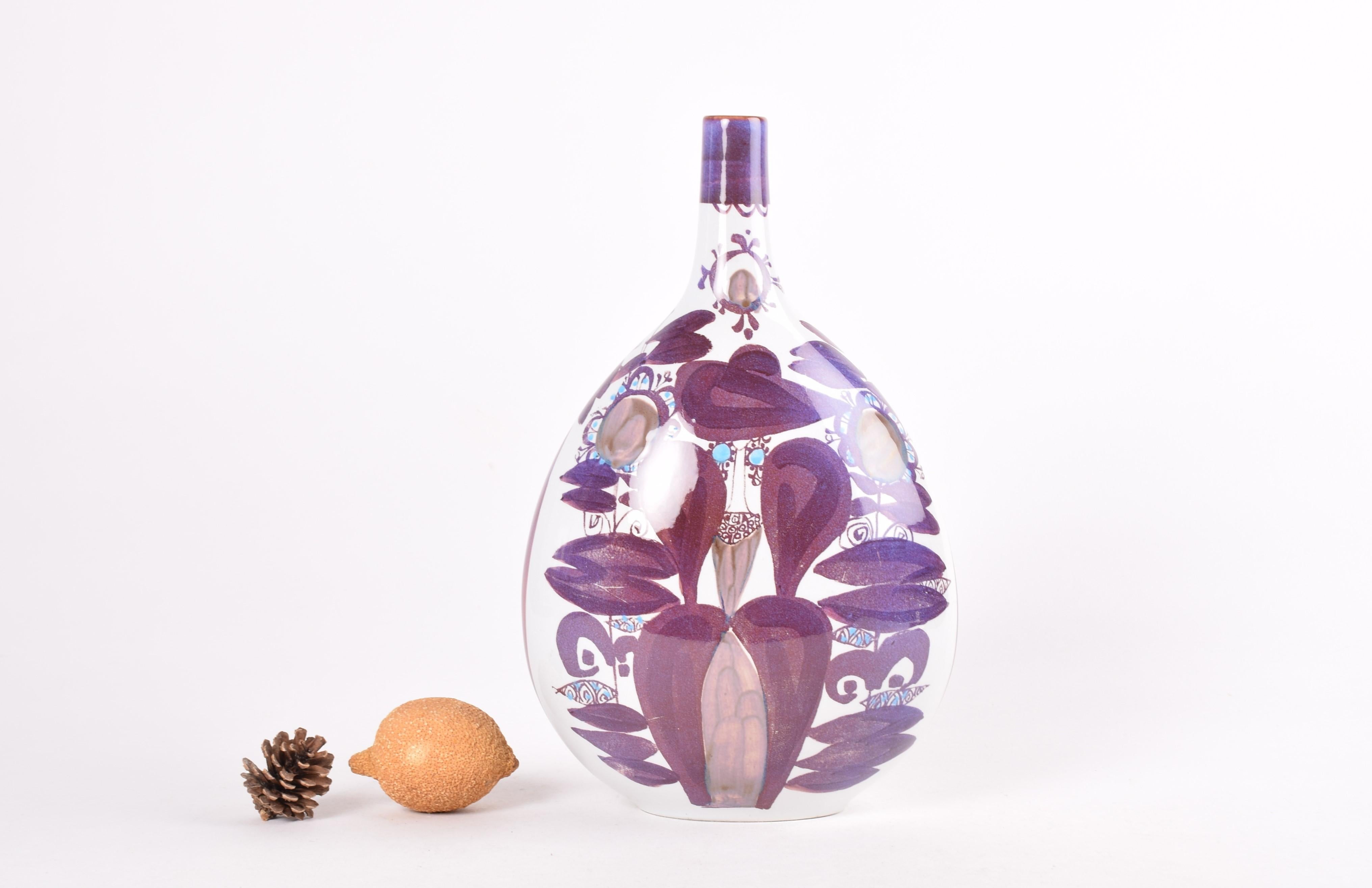 Hohe Vase aus der Aluminia (späterer Markenname Royal Copenhagen) Tenera-Serie. Das handgemalte abstrakte Blumendekor wurde in den 1960er Jahren von Kari Christensen entworfen. Er hat das gleiche Dekor auf Vorder- und Rückseite.

Diese Vase stammt