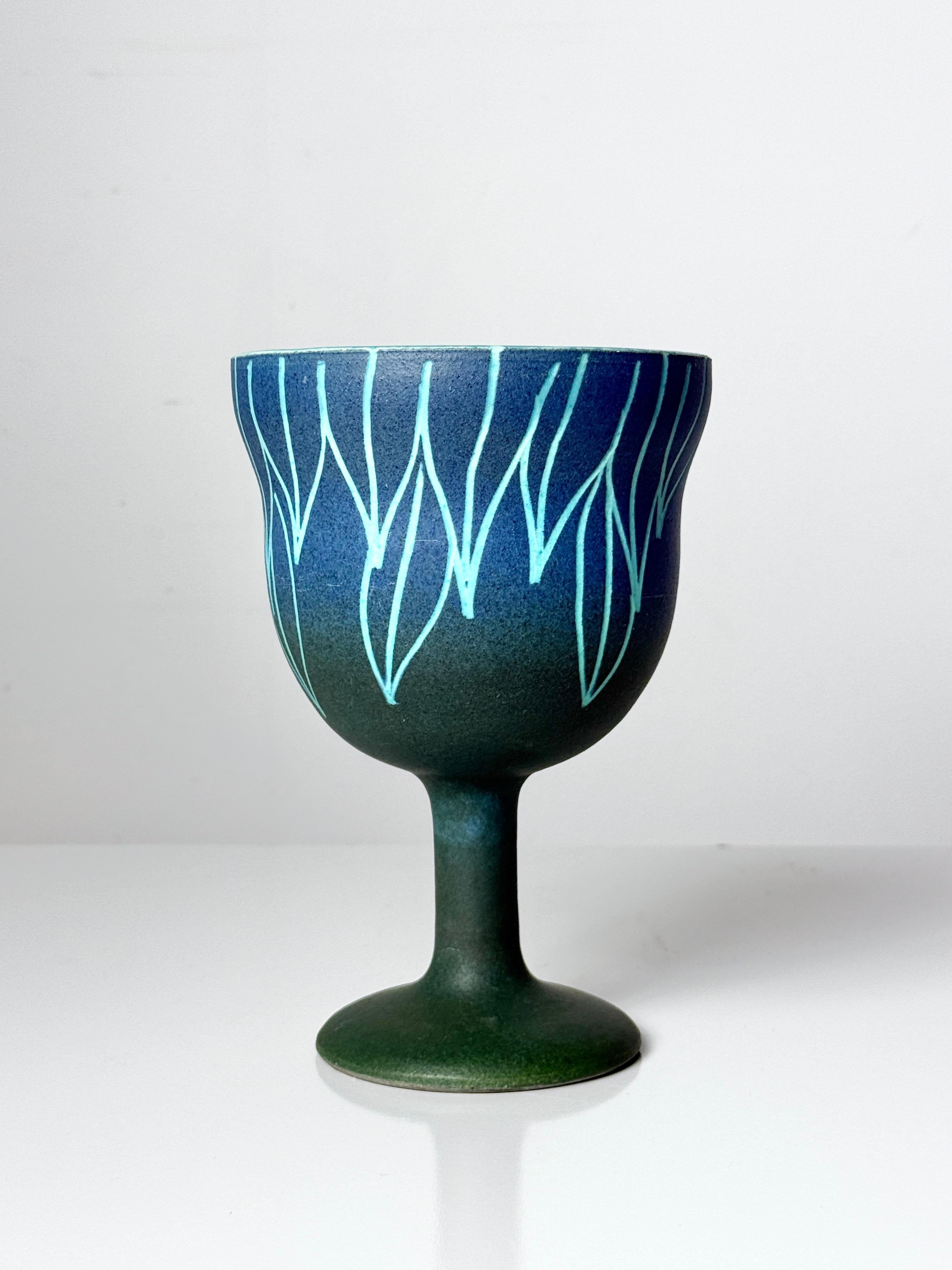 Vaso cáliz poco común diseñado por Alvino Bagni para Raymor hacia la década de 1960

Forma única en un ombre de esmaltes azul y verde con decoración abstracta incisa de hojas

Marcado en la parte inferior con la etiqueta Raymor original