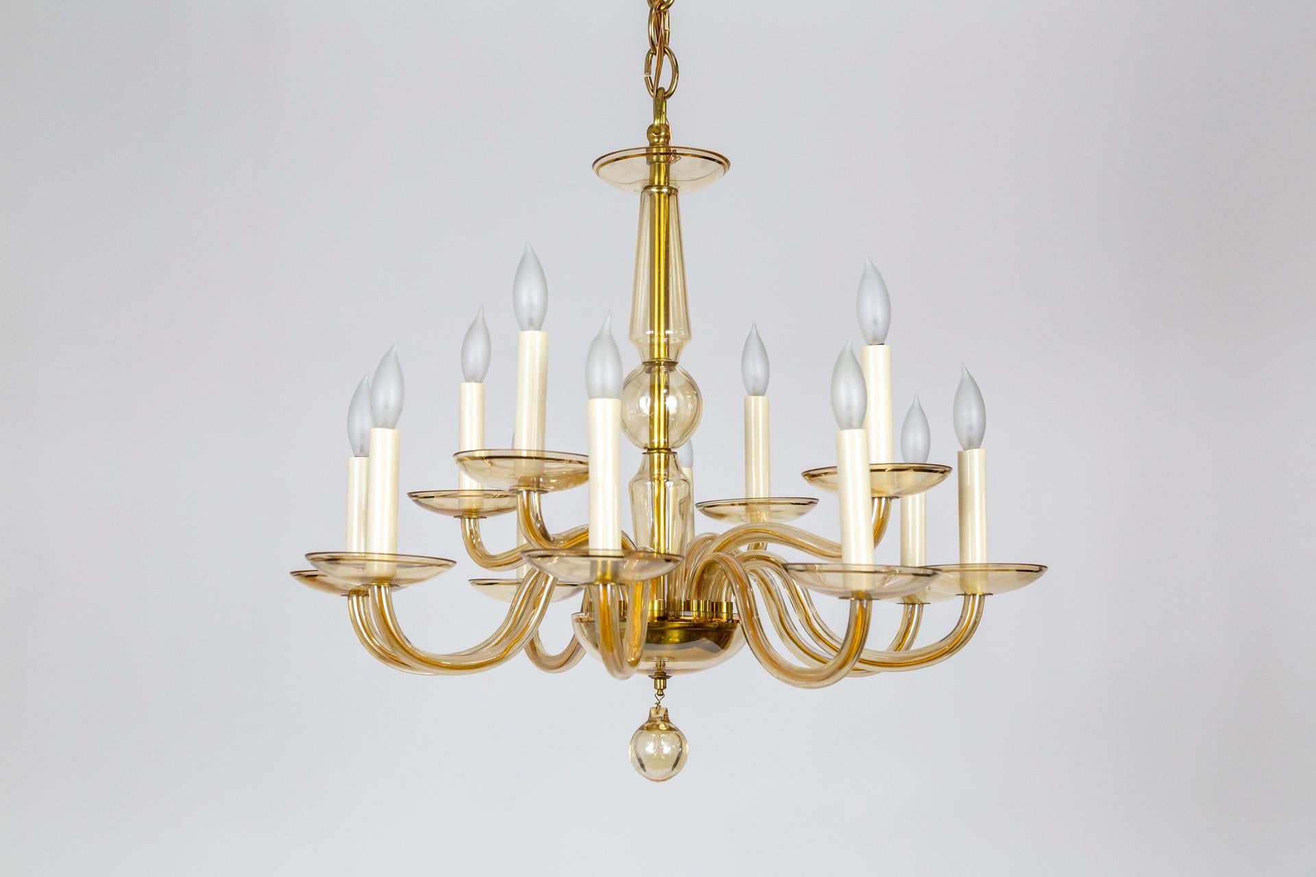 A 1960's, Italian chandelier in the modern, neoclassical tradition. 12 scroll arms in champagne toned glass with gold pin stripes around the bobéches rims and glass covered brass bottom bowl and stem. Simply beautiful. Measures: 23