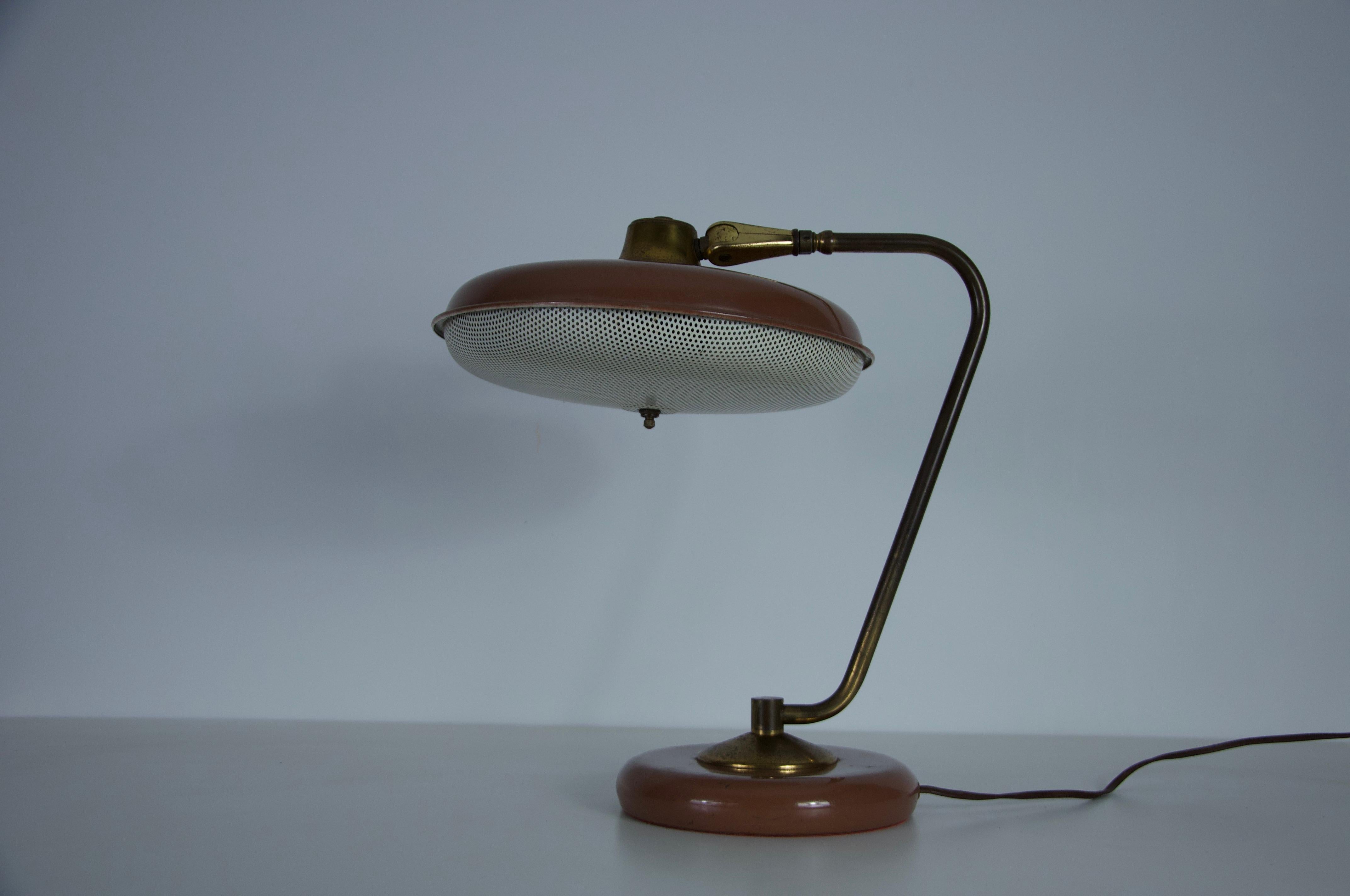 This striking Mid-Century American table lamp from the 1960s features an elegant combination of brass and painted metal, reflecting the sleek, space-age aesthetics of the era. The distinctive perforated lower shade allows for a beautifully diffused